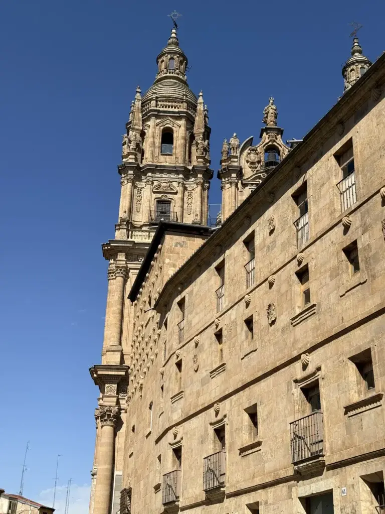 Fachada lateral de la Casa de las Conchas con las torres de La Clerecía al fondo — Foto propia La Maleta Inquieta, junio 2026