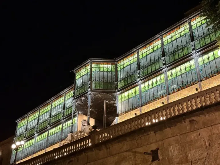 Gran vidriera del patio de Casa Lis iluminada de noche con cristales verdes, amarillos y naranjas — Foto propia La Maleta Inquieta, junio 2026