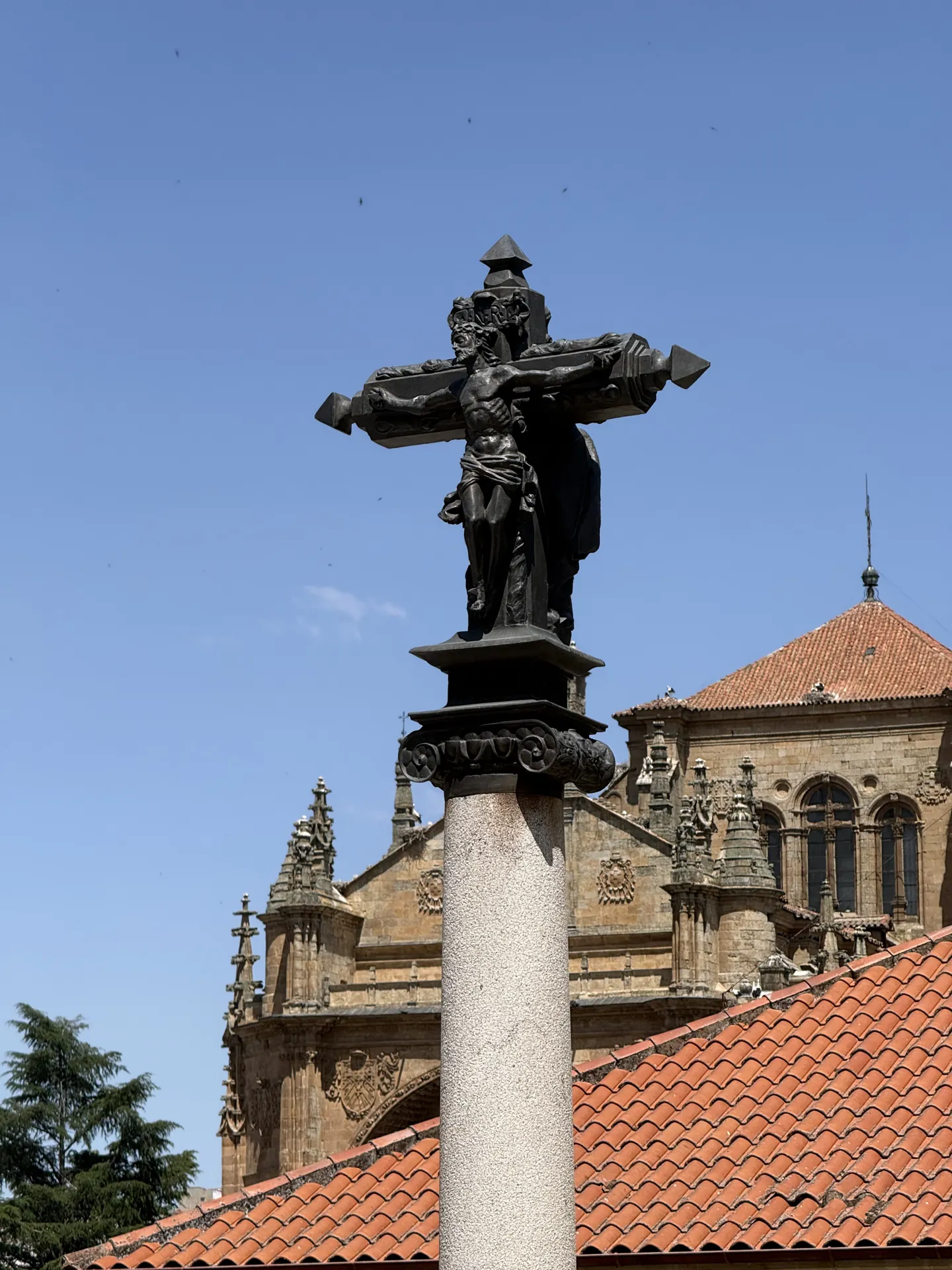 Crucifijo de bronce en una calle de Salamanca con la Catedral al fondo, en el recorrido de las procesiones. Foto propia La Maleta Inquieta, septiembre 2026