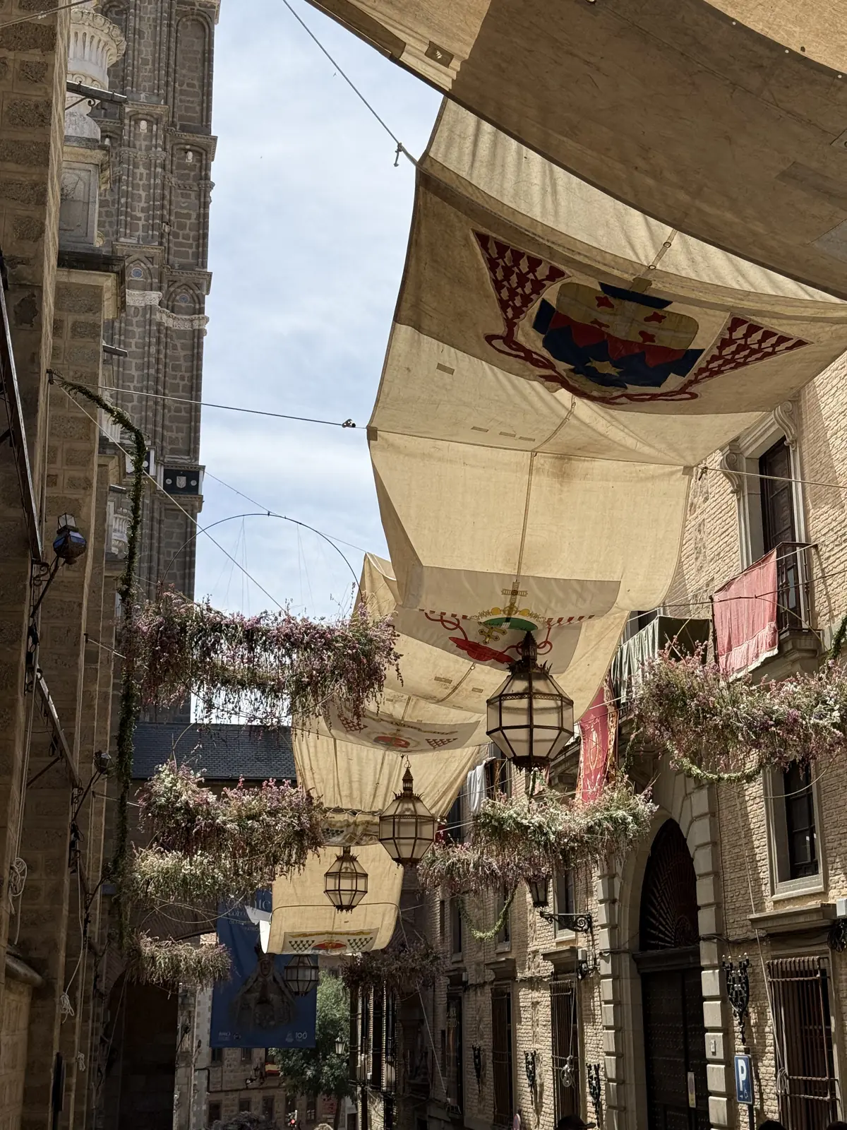 Toldos con escudos heráldicos sobre una calle de Toledo junto a la torre de la Catedral en el Corpus — Foto propia La Maleta Inquieta, junio 2026