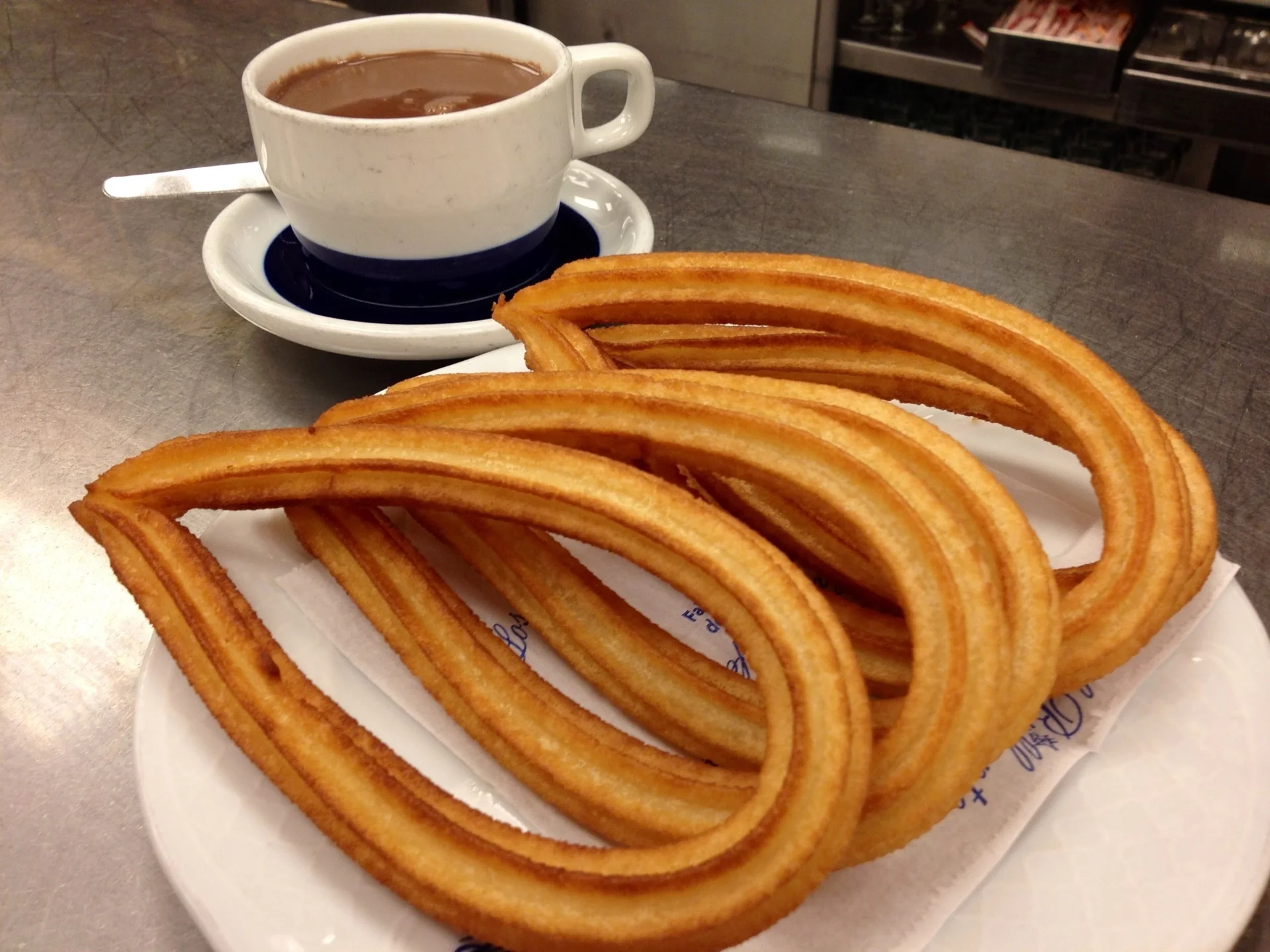 Taza de chocolate espeso con churros al lado en una mesa de chocolatería del centro de Madrid. Foto propia La Maleta Inquieta, julio 2026