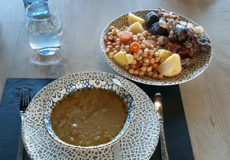 Cocido madrileño servido con sopa, garbanzos, verduras y carnes en dos platos