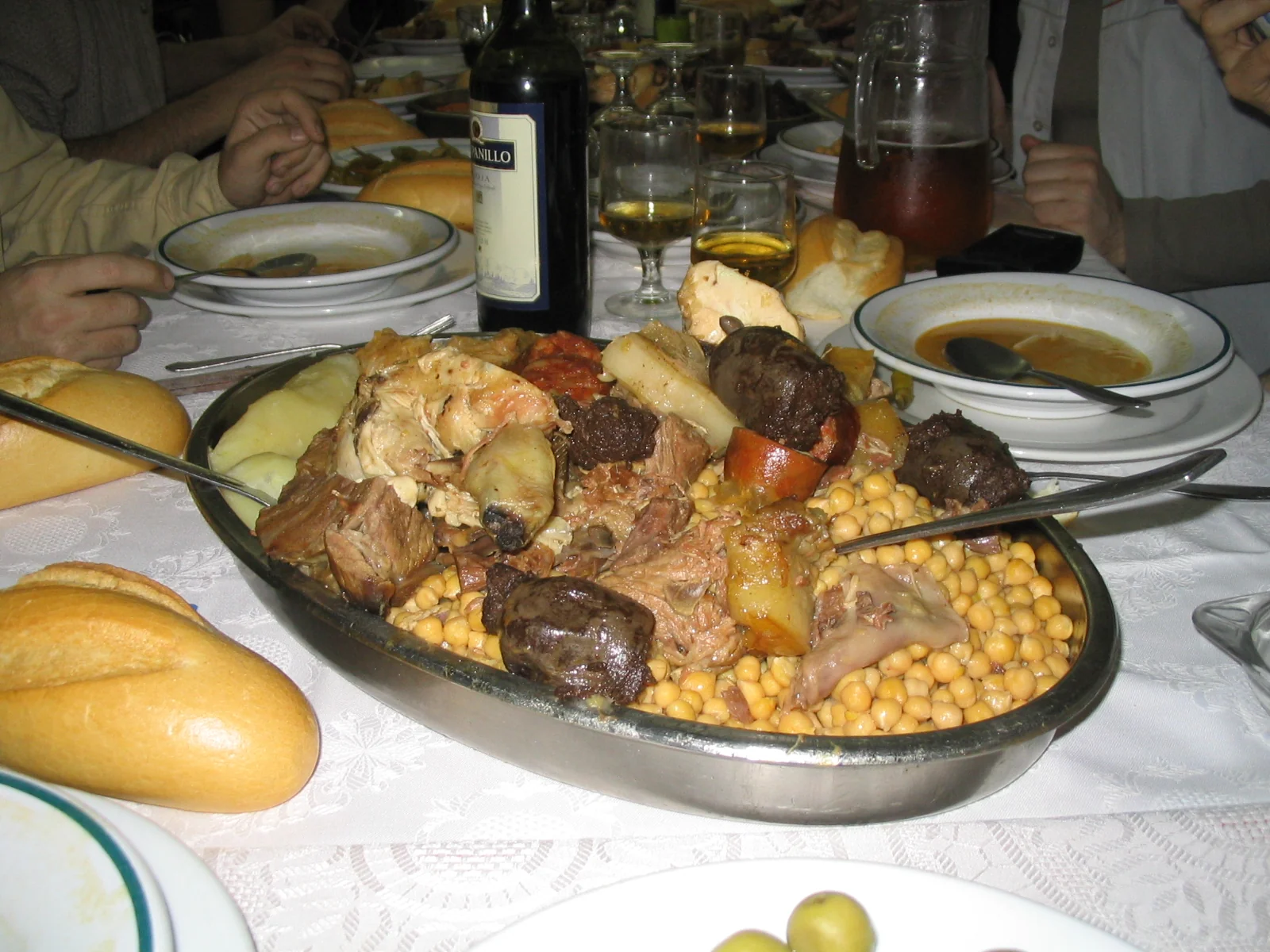 Fuente de cocido madrileño con garbanzos, carnes, morcilla y chorizo servida en la mesa