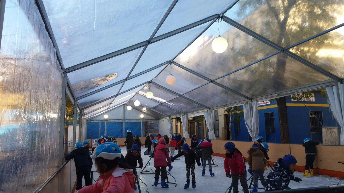 Pista de hielo al aire libre con patinadores y luces navideñas en una plaza de Madrid