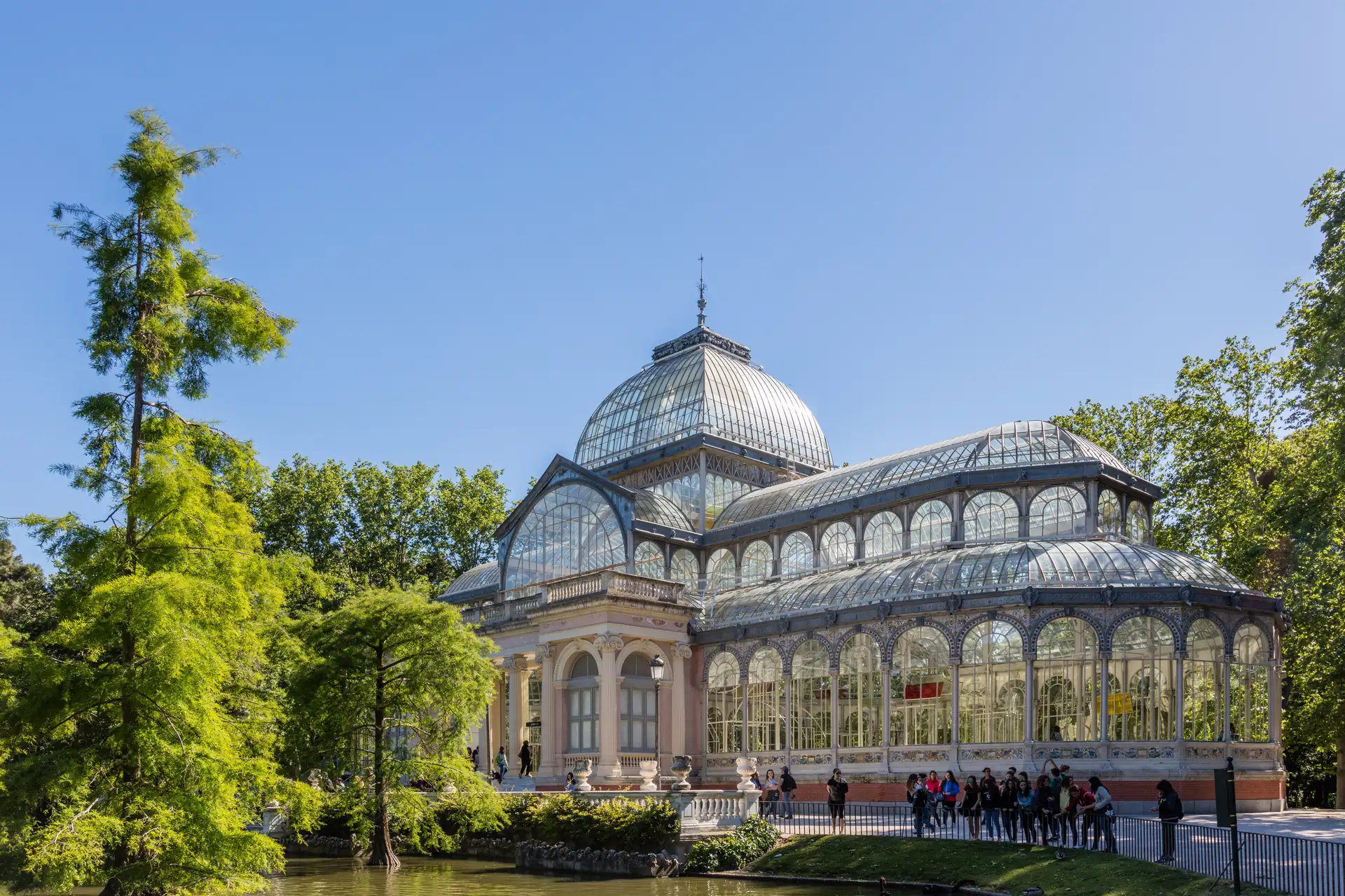 Palacio de Cristal del Retiro con su cúpula acristalada junto al estanque y árboles, La Maleta Inquieta