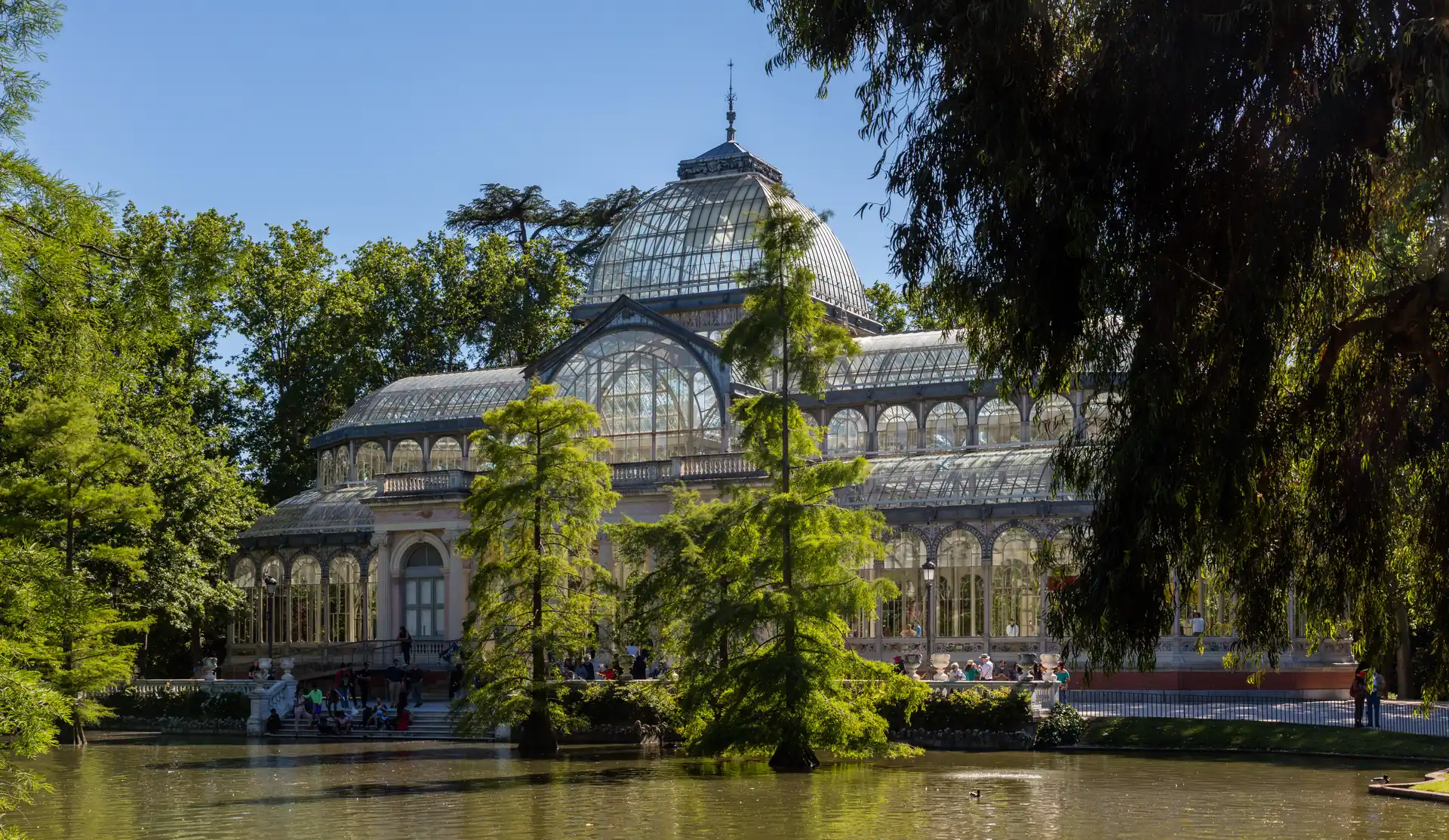 Cúpula y estructura de hierro y cristal del Palacio de Cristal del Retiro reflejada en el estanque. Foto propia La Maleta Inquieta, 2026.