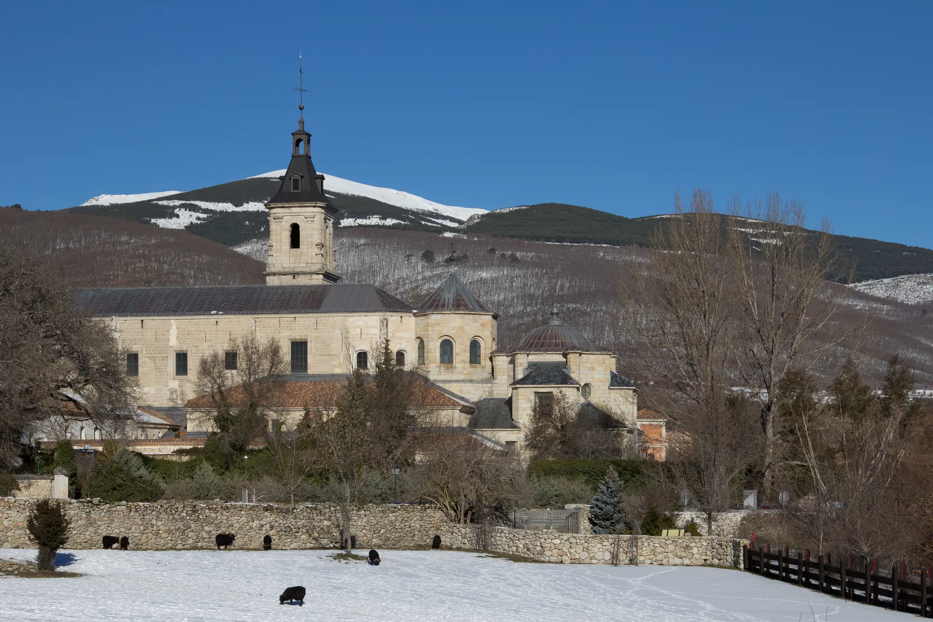 Monasterio de El Paular en Rascafría en invierno, con prado nevado y la Sierra de Guadarrama al fondo — La Maleta Inquieta
