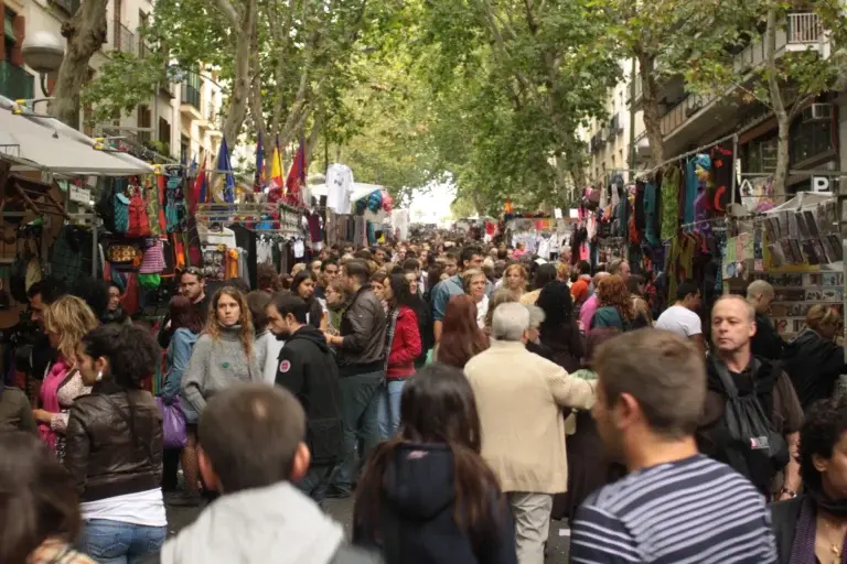 El Rastro de Madrid abarrotado de gente entre puestos de ropa y complementos bajo los árboles