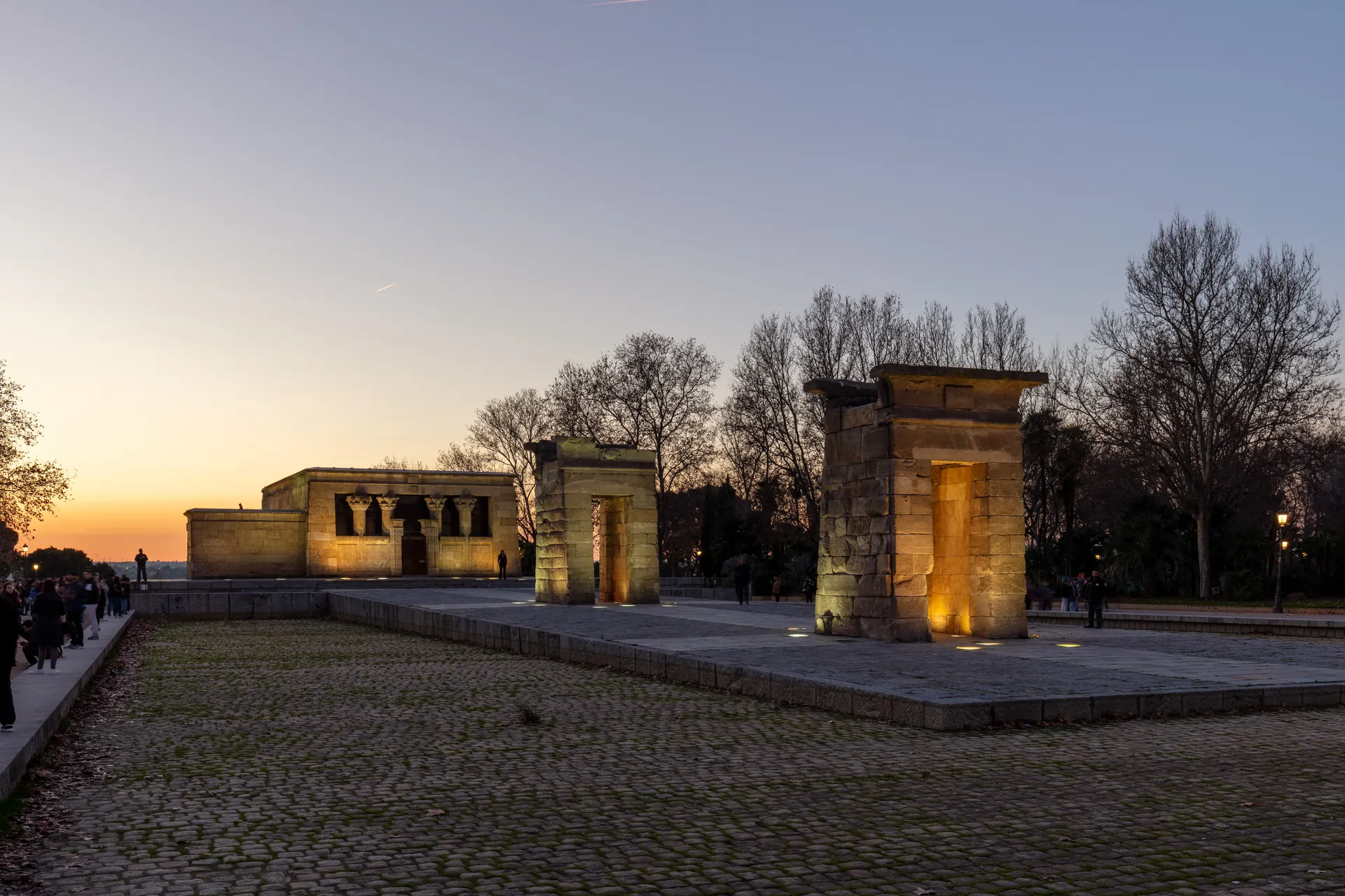 Templo de Debod iluminado al atardecer, con sus puertas de piedra recortadas contra el cielo.