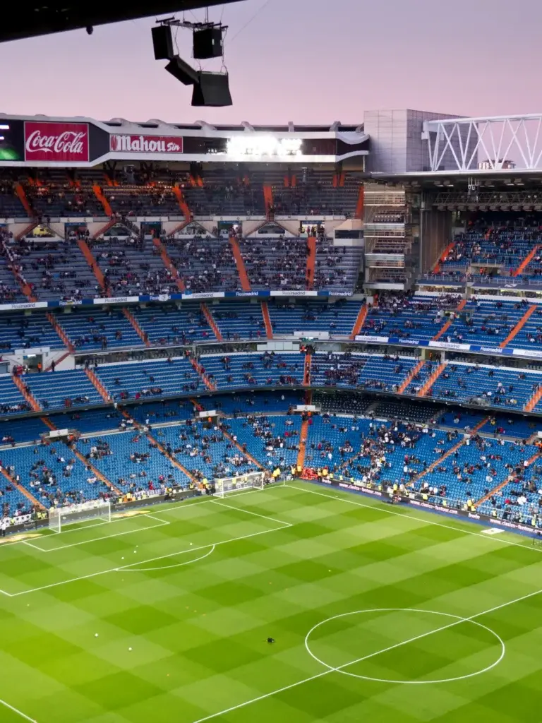 Interior del estadio Santiago Bernabéu con el césped y las gradas azules antes de un partido — La Maleta Inquieta
