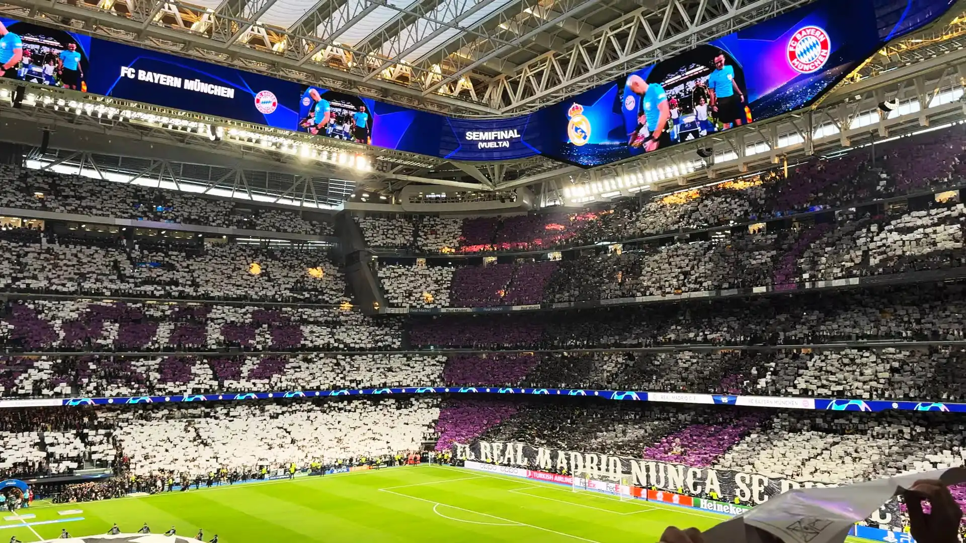 Estadio Santiago Bernabéu lleno con un tifo blanco y morado bajo la cubierta en una noche de Champions