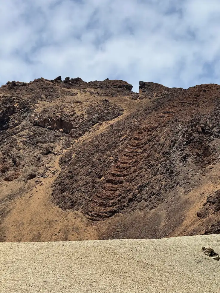 Ladera volcánica del Teide con coladas de lava marrón rojiza y arena amarilla. Foto propia La Maleta Inquieta, agosto 2026.