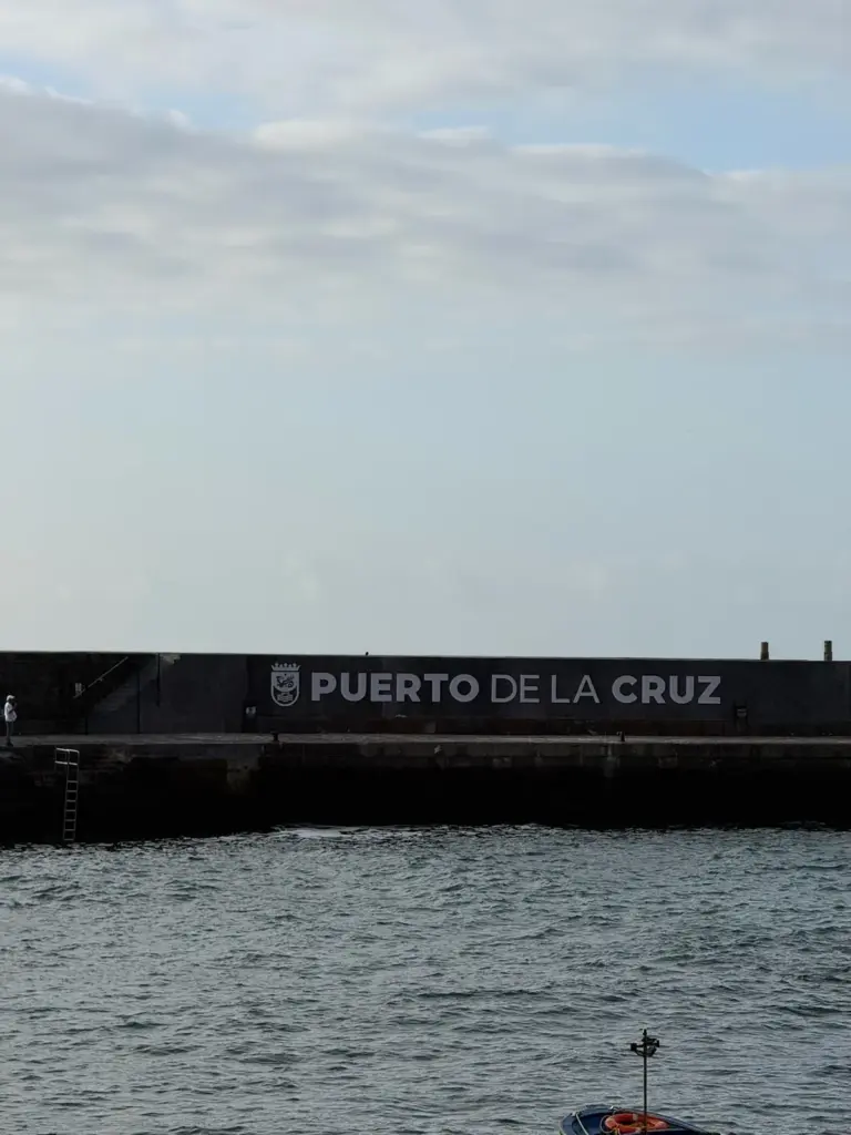 Muro negro con letras 'Puerto de la Cruz' junto al mar. Foto propia La Maleta Inquieta, julio 2026.