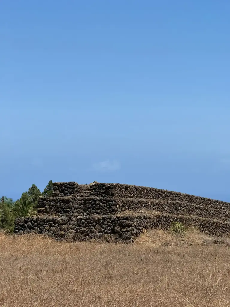 Pirámide escalonada de piedra volcánica en Güímar con hierba seca alrededor. Foto propia La Maleta Inquieta, julio 2026.