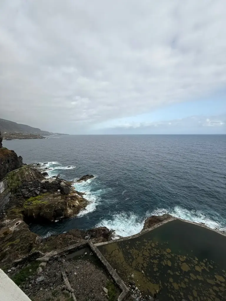 Piscina natural en la costa de Tenerife con olas rompiendo y cielo nublado. Foto propia La Maleta Inquieta, julio 2026.