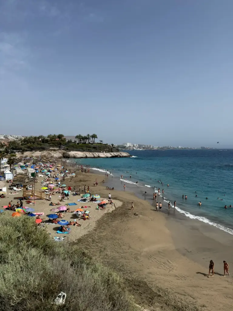 Playa de arena clara con sombrillas de colores y bañistas en Costa Adeje. Foto propia La Maleta Inquieta, agosto 2026.