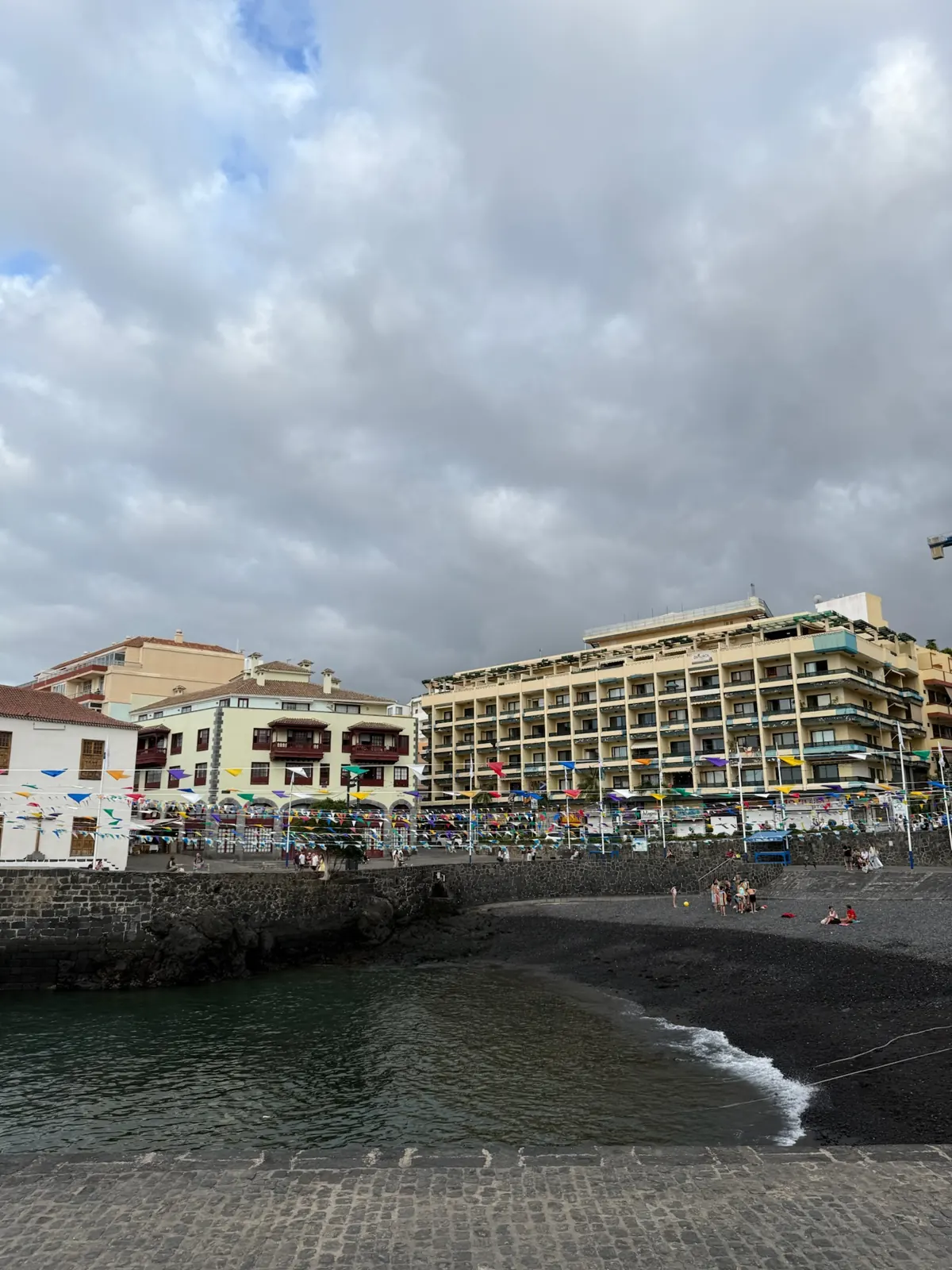 Banderines de fiesta sobre la playa de arena negra de Puerto de la Cruz. Foto propia La Maleta Inquieta, agosto 2026.
