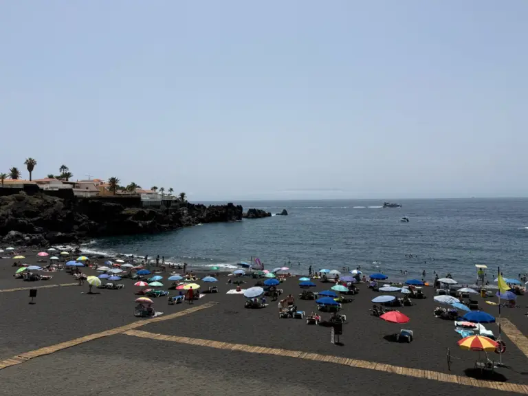 Playa de arena negra volcánica con sombrillas de colores en el sur de Tenerife. Foto propia La Maleta Inquieta, agosto 2026.