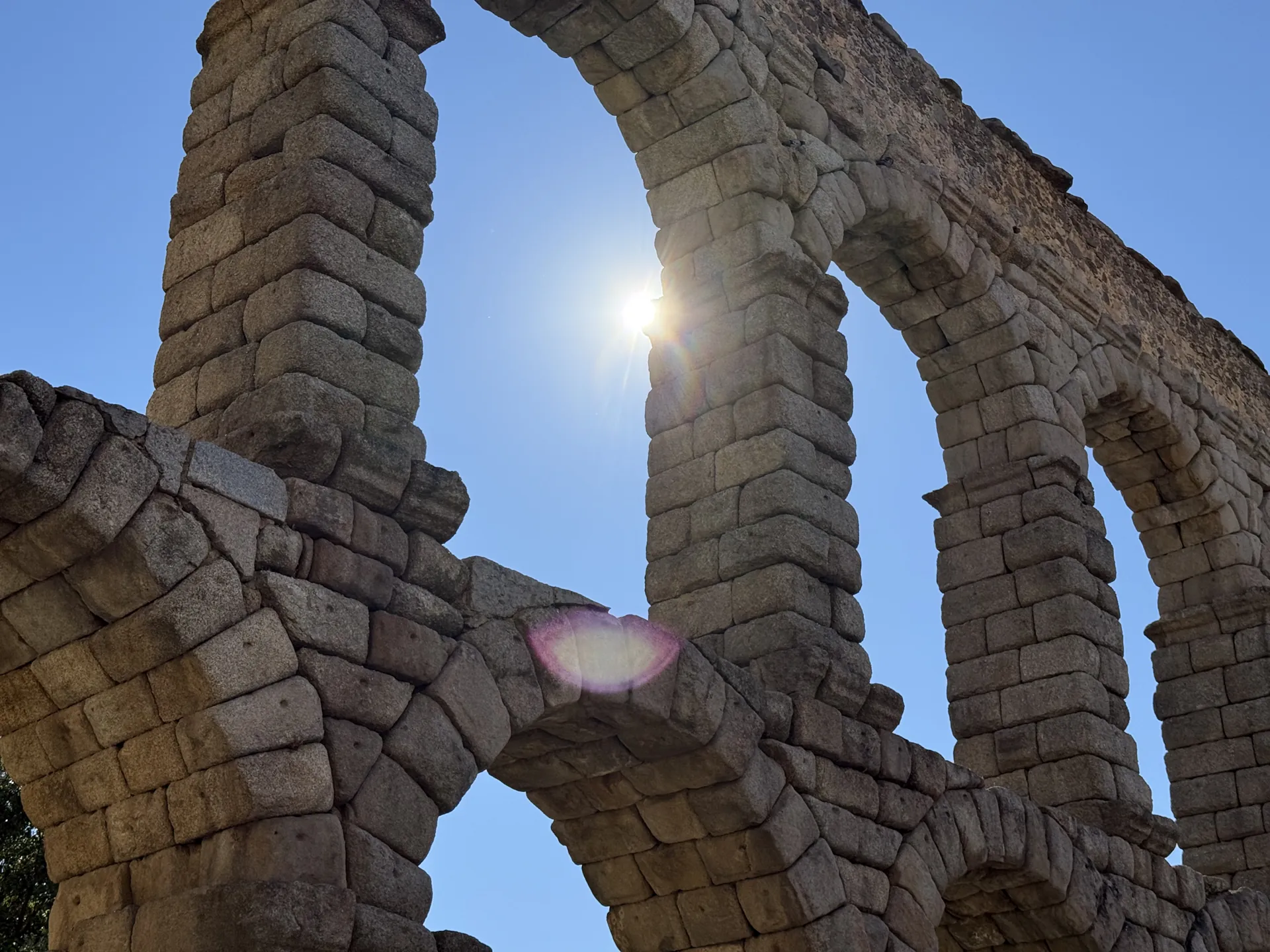 Arcos del Acueducto de Segovia vistos desde abajo con el sol brillando a contraluz entre la piedra. Foto propia La Maleta Inquieta, septiembre 2026.