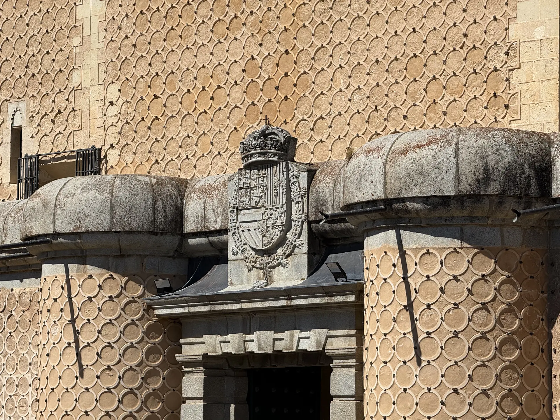 Fachada del Alcázar de Segovia con esgrafiado de círculos, escudo heráldico coronado y balcón con balaustrada. Foto propia La Maleta Inquieta, septiembre 2026.
