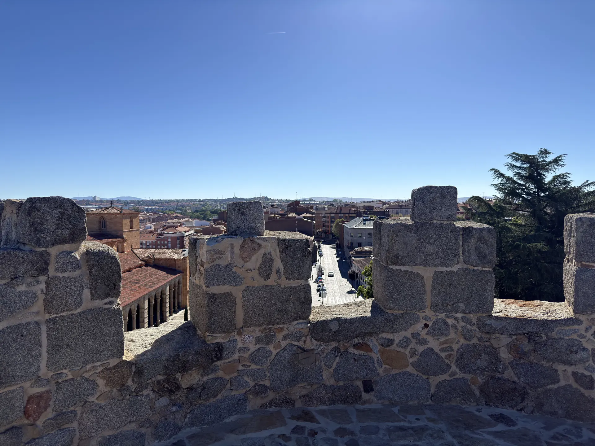 Almenas del adarve sobre la Puerta de San Vicente de Ávila, con la basílica y una calle recta hacia el norte. Foto propia La Maleta Inquieta, septiembre 2026.