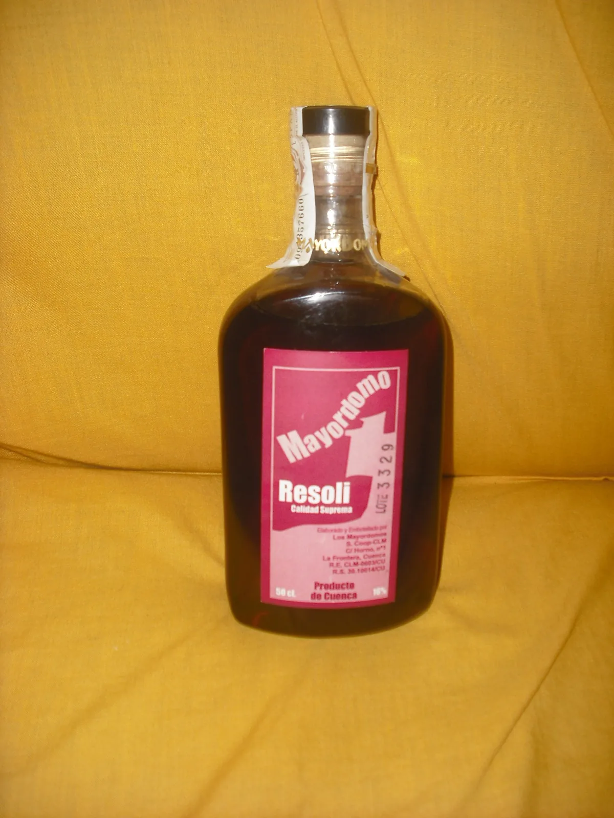 Botella de resolí Mayordomo, el licor tradicional de Cuenca, fotografiada sobre un fondo de tela amarilla