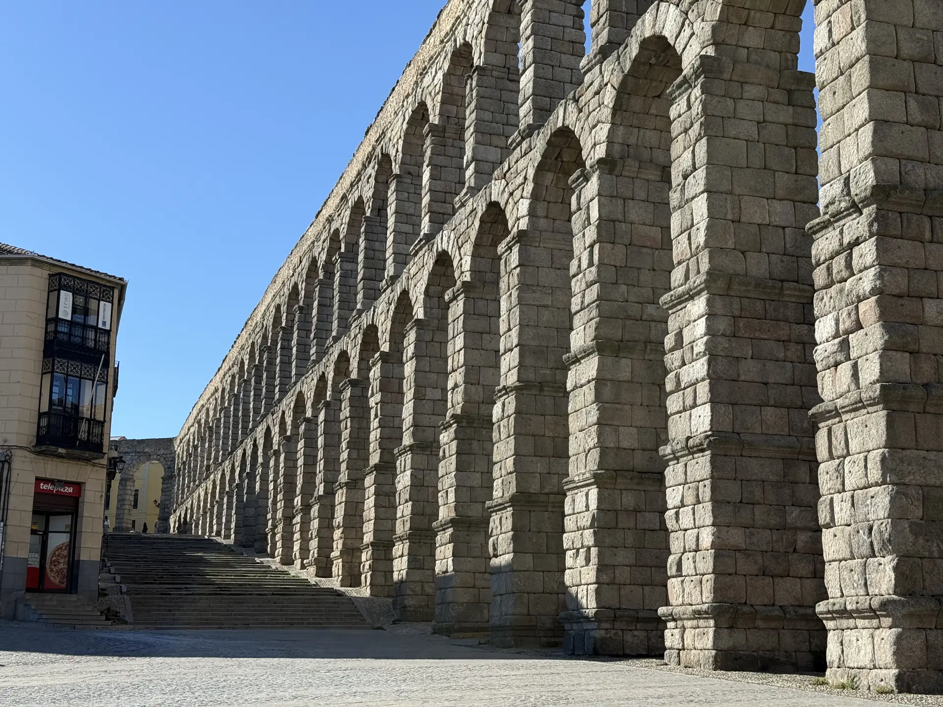 Calle que pasa bajo los arcos del Acueducto de Segovia con edificios históricos a los lados. Foto propia La Maleta Inquieta, septiembre 2026