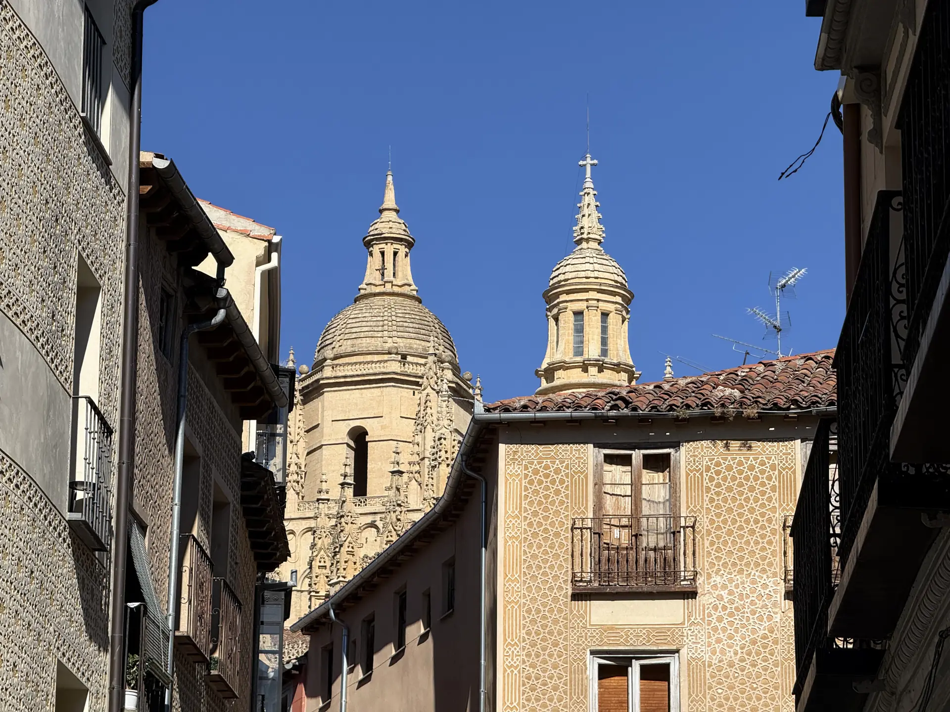 Calle estrecha del casco histórico con las cúpulas de la Catedral de Segovia al fondo y edificio con esgrafiado geométrico. Foto propia La Maleta Inquieta, septiembre 2026.