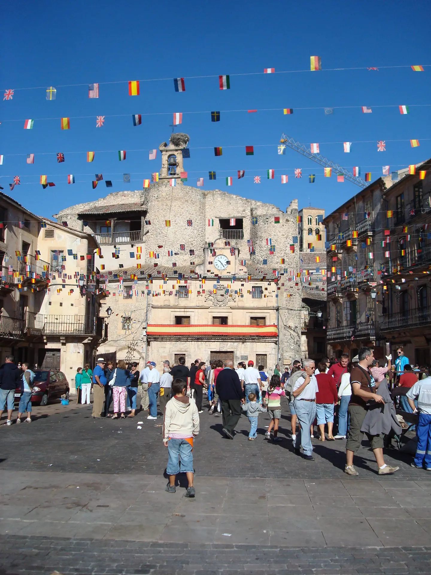 La plaza porticada de Sepulveda llena de gente durante una fiesta, con el ayuntamiento al fondo.