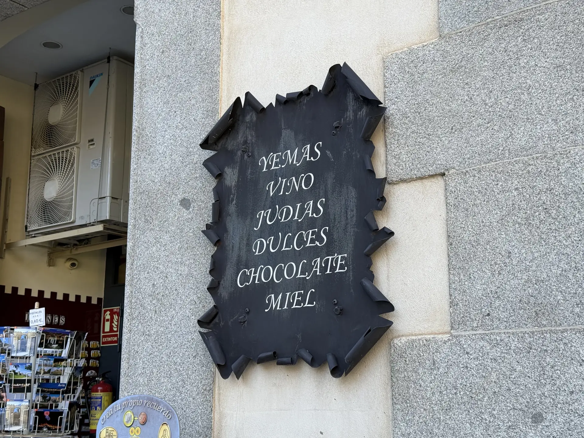 Cartel de hierro con yemas, vino, judías, dulces, chocolate y miel en una tienda junto a la catedral de Ávila. Foto propia La Maleta Inquieta, septiembre 2026