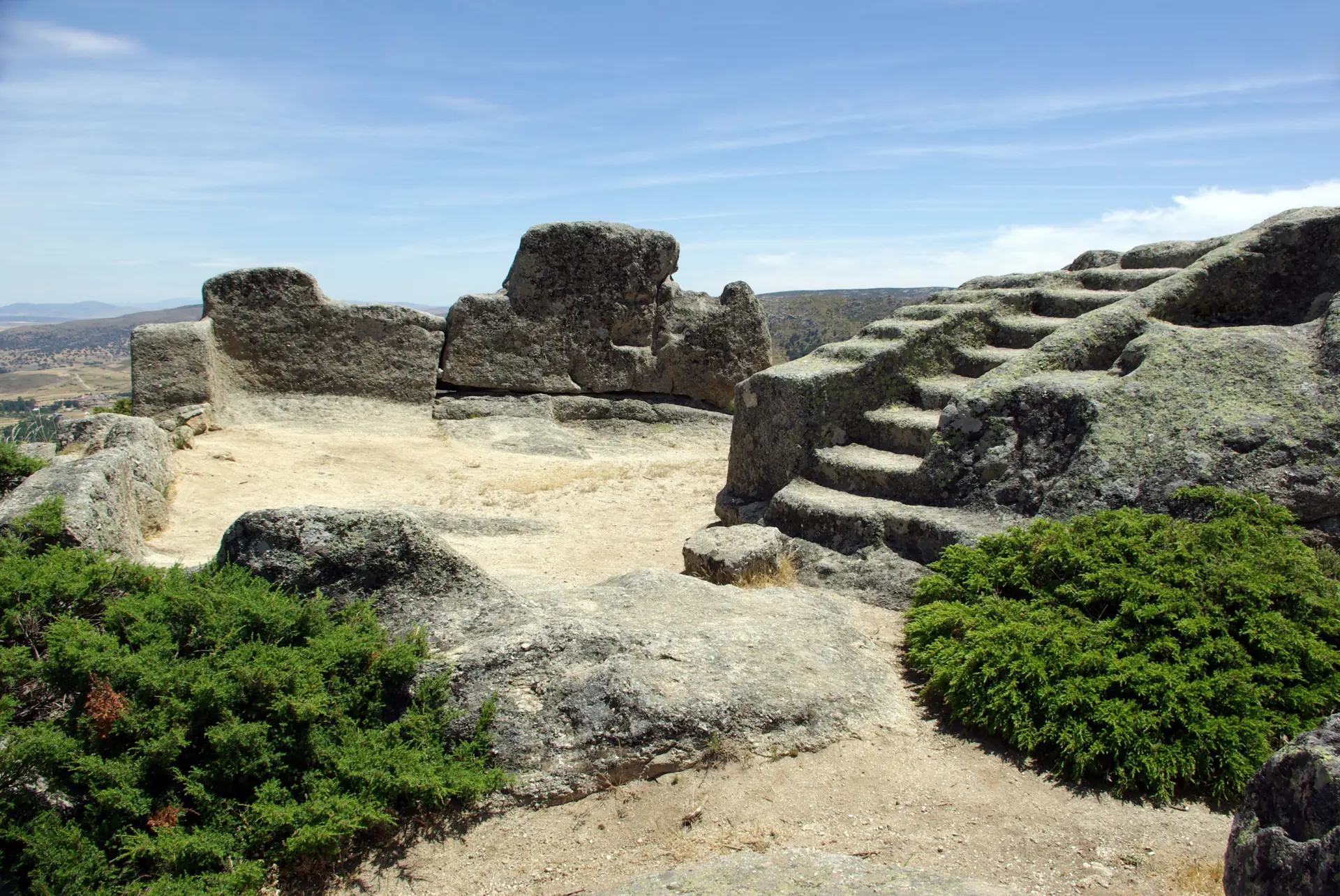Altar de sacrificios del castro vetón de Ulaca, una gran roca de granito con escalones tallados junto a una plataforma y la llanura abulense al fondo