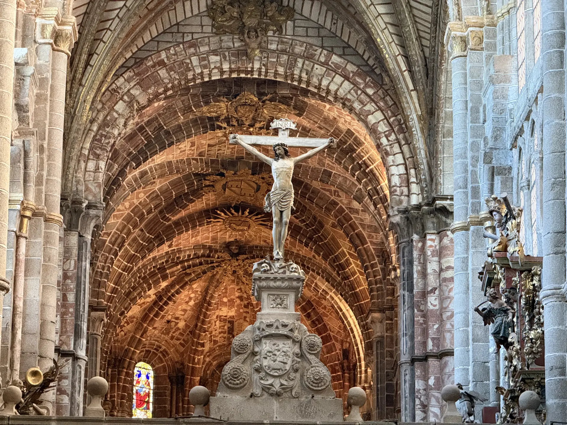 Crucifijo sobre el trascoro de la catedral de Ávila, ante la bóveda de piedra sangrante rojiza de la cabecera. Foto propia La Maleta Inquieta, septiembre 2026.