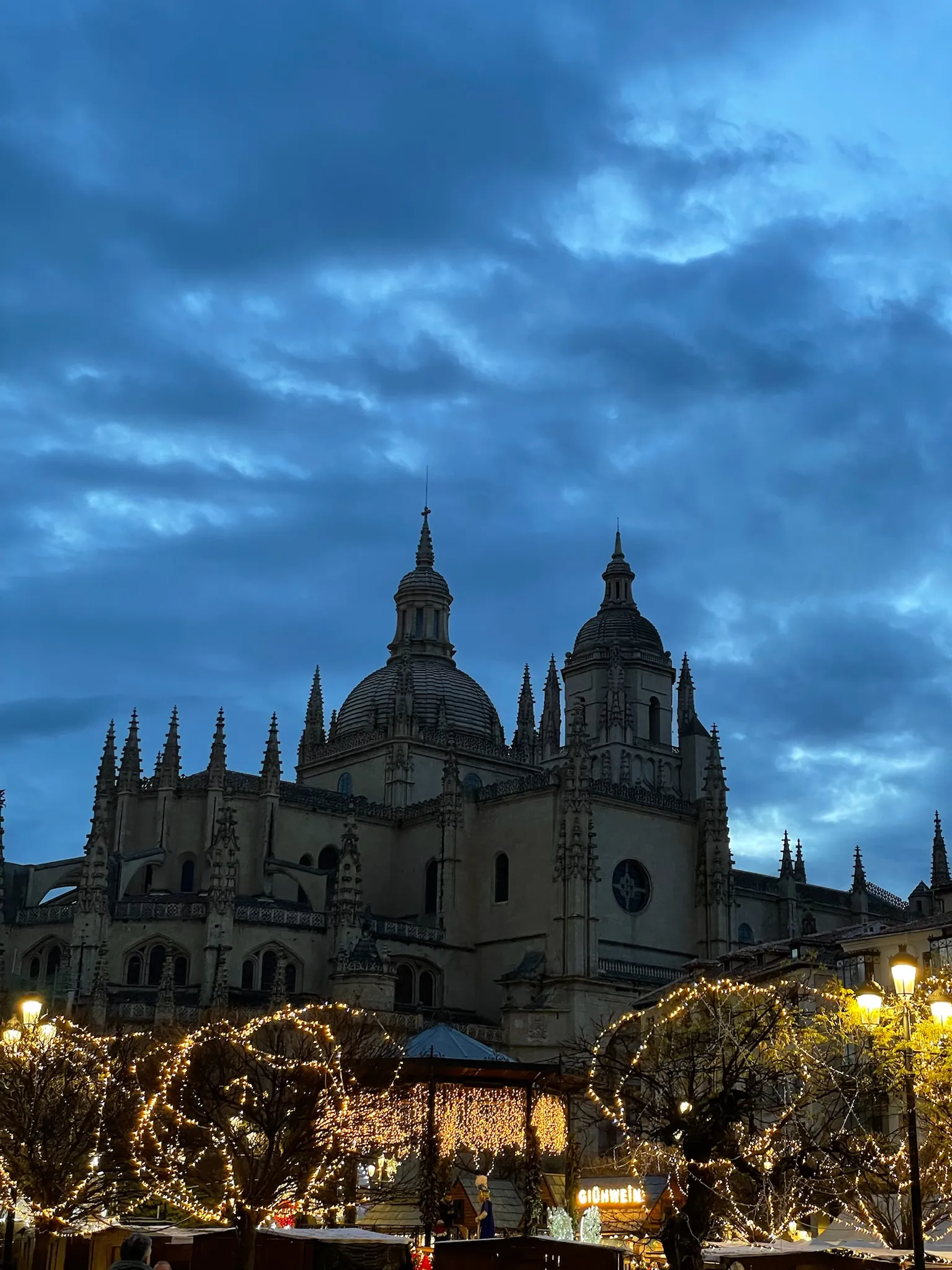 Cúpulas de la catedral de Segovia recortadas contra el cielo azul oscuro del anochecer, con los árboles de la plaza iluminados. Foto propia La Maleta Inquieta, octubre 2026
