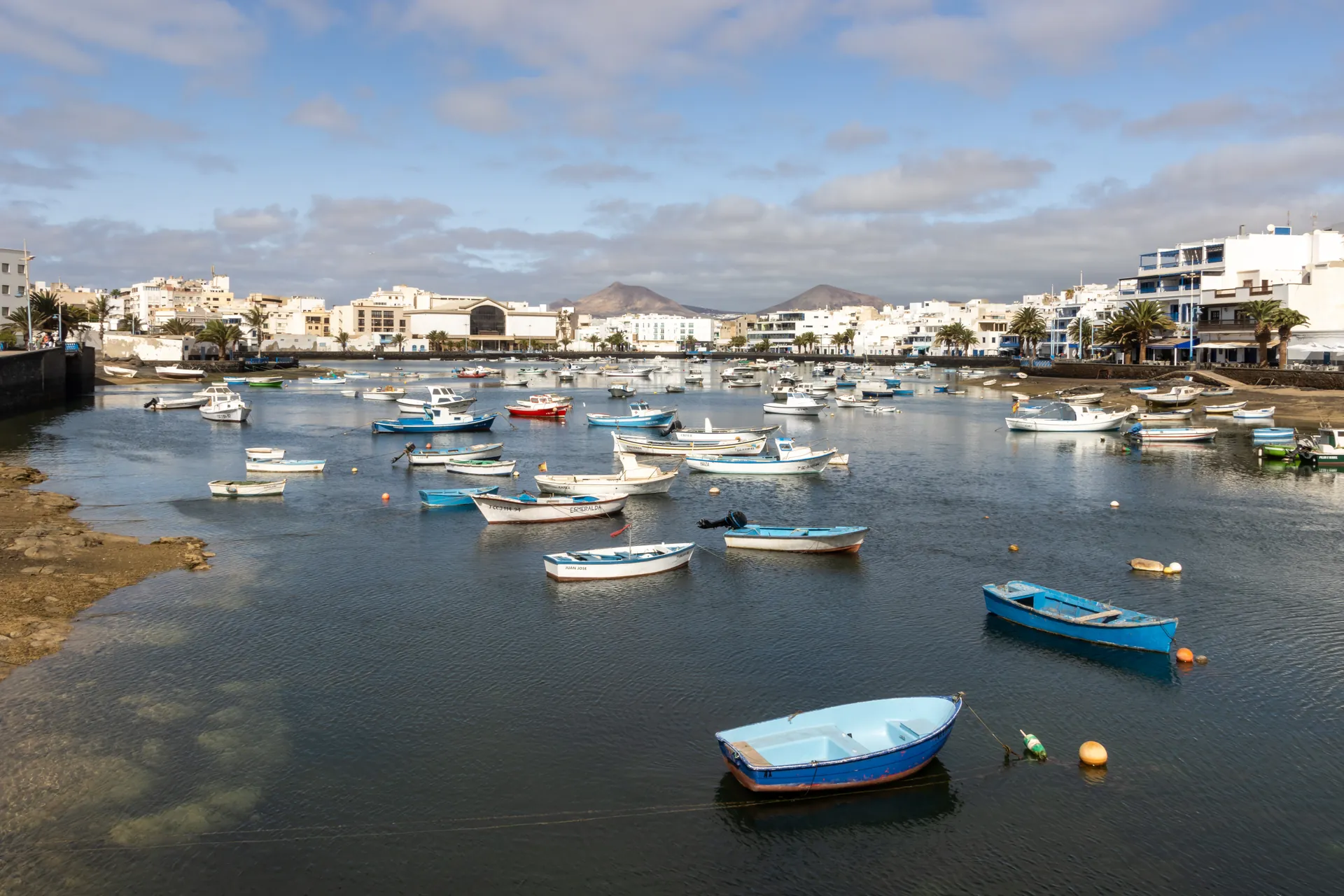 Barcas de pesca amarradas en el Charco de San Ginés de Arrecife, con las casas blancas del paseo y los montes de Lanzarote al fondo
