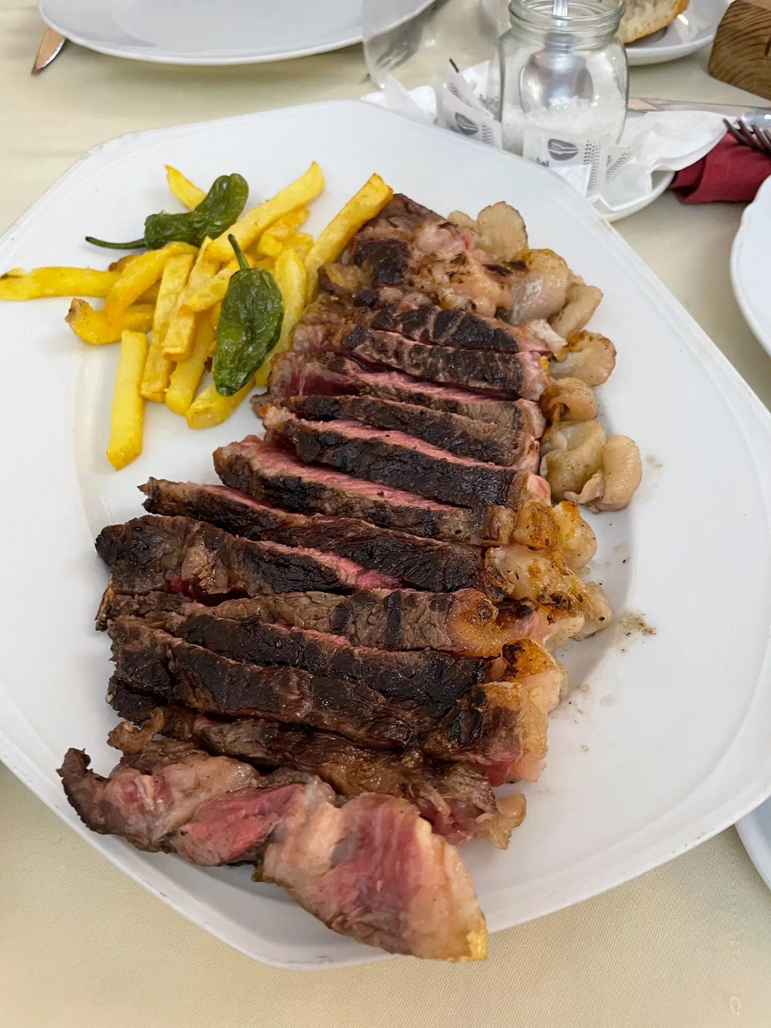 Chuletón fileteado en lonchas con patatas fritas y pimientos de padrón servido en plato. Foto propia La Maleta Inquieta, septiembre 2026