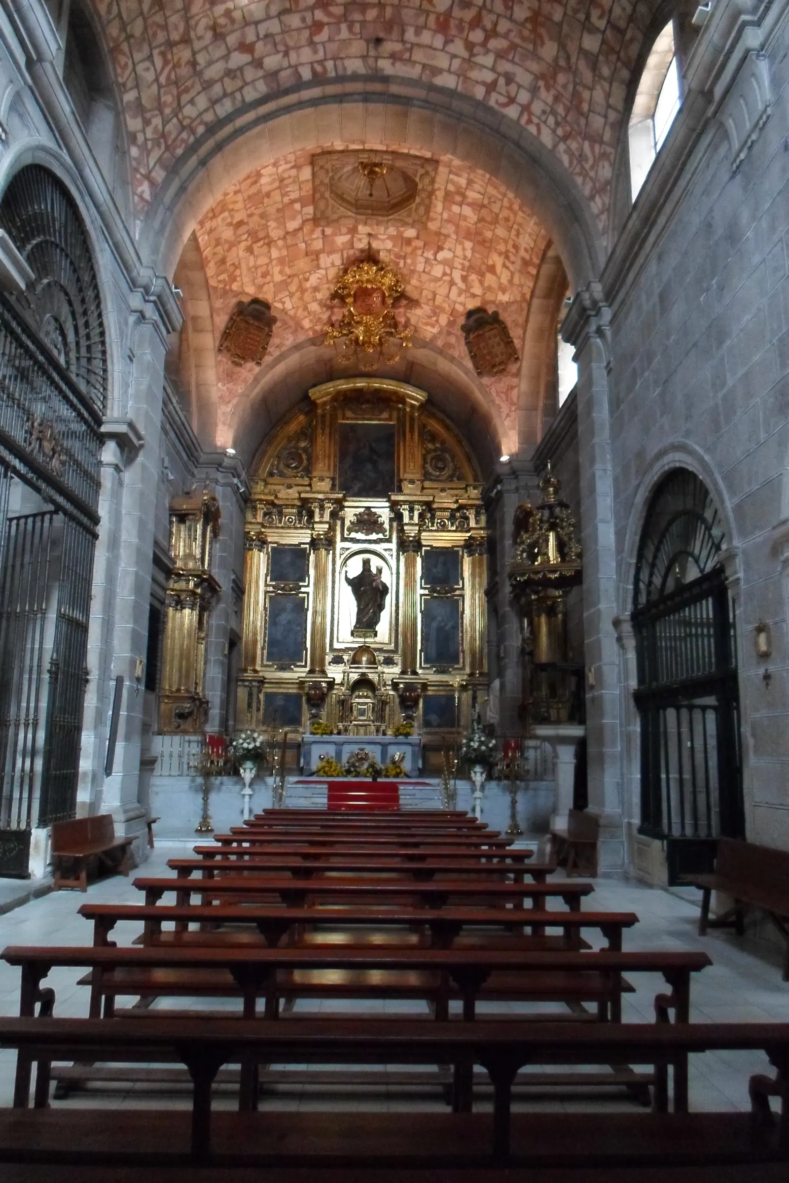 Nave de la iglesia del convento de San José de Ávila con bancos de madera, bóveda decorada y retablo dorado al fondo