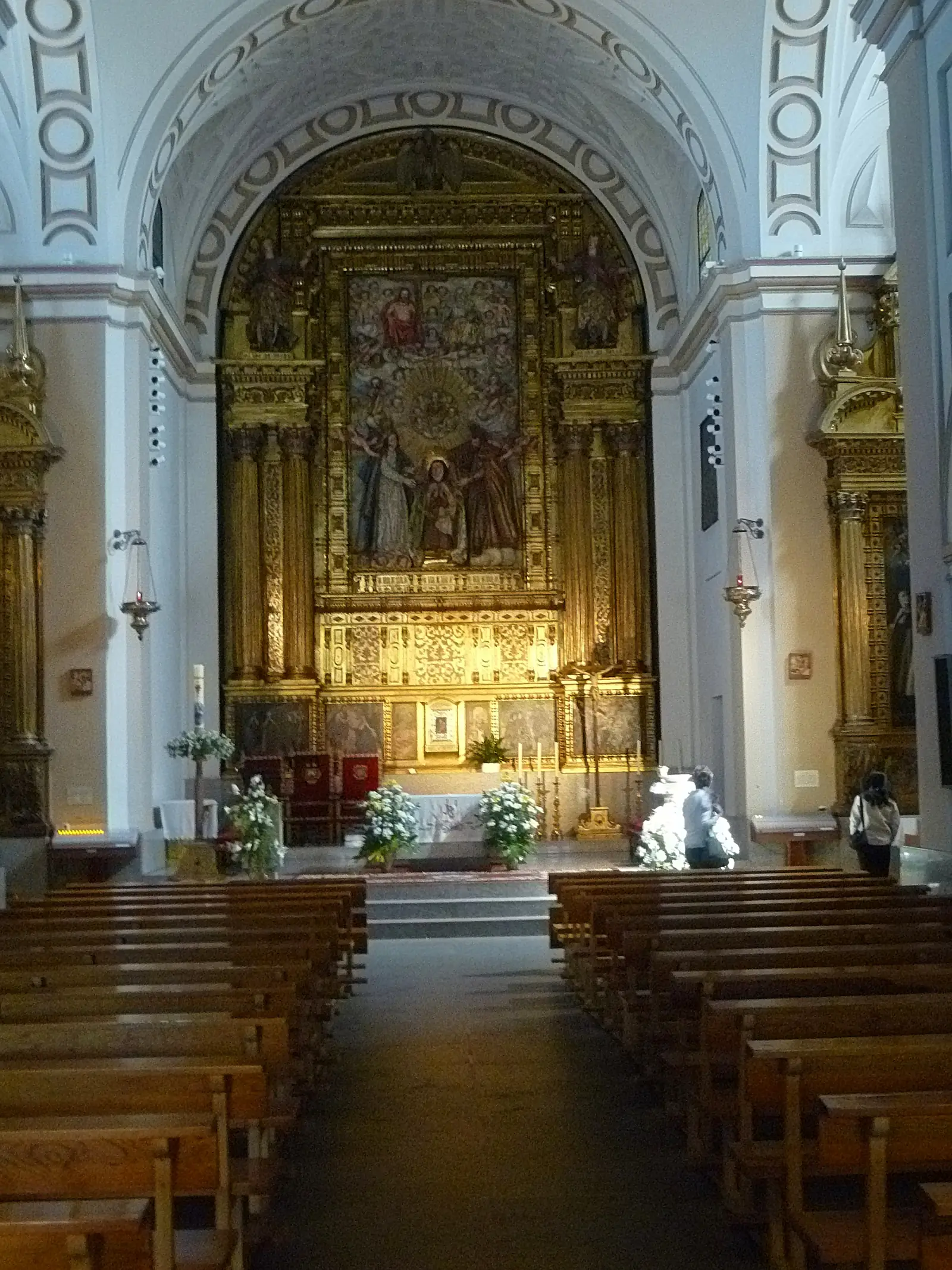 Nave blanca de la iglesia del convento de Santa Teresa de Ávila, con bancos de madera y retablo mayor dorado al fondo bajo la bóveda de casetones