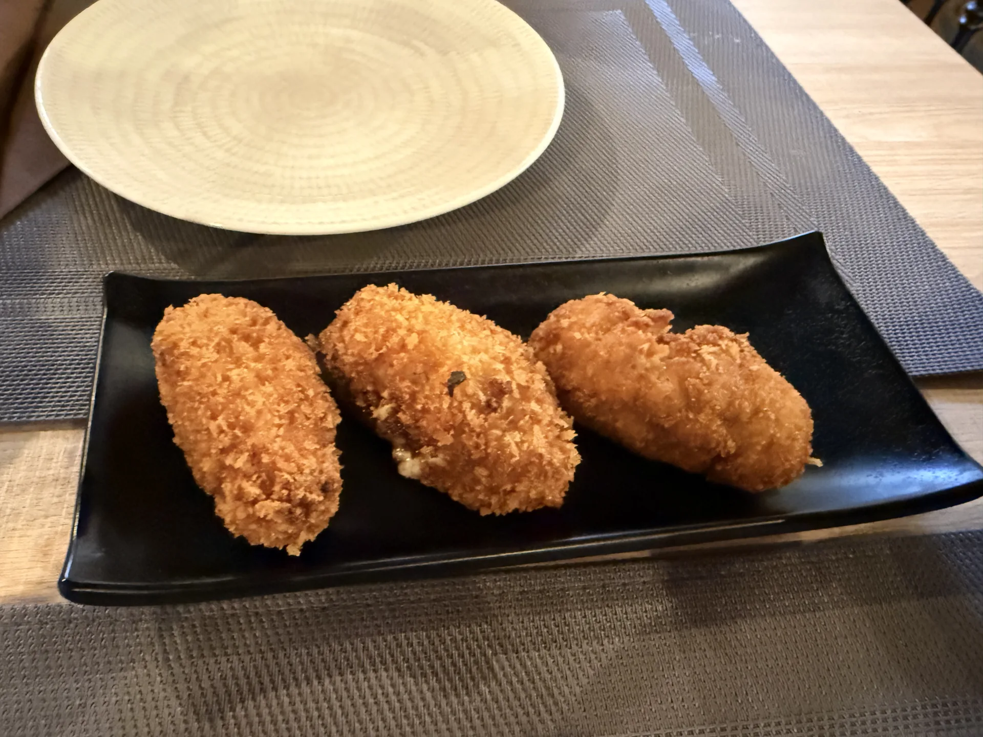 Tres croquetas caseras de rebozado crujiente en una bandeja negra de pizarra servidas en Redes Bar, Ávila. Foto propia La Maleta Inquieta, septiembre 2026.