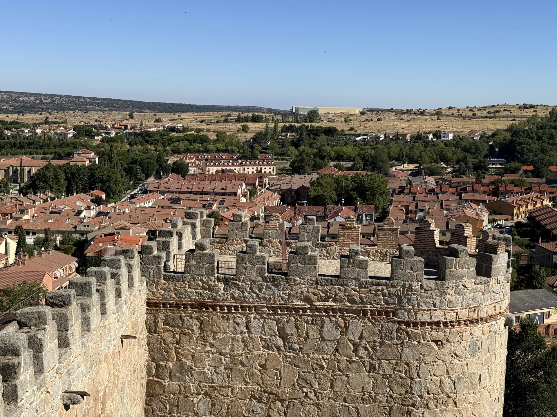 Cubo almenado del tramo norte de la muralla de Ávila sobre los tejados y los campos del norte, desde el adarve. Foto propia La Maleta Inquieta, septiembre 2026.