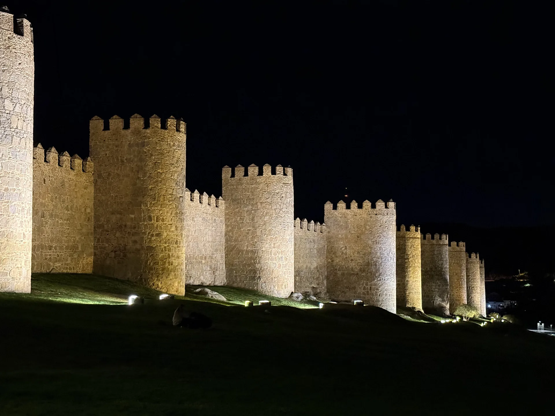 Cubos almenados del lienzo norte de la muralla de Ávila con luz cálida en plena noche, en encuadre cerrado. Foto propia La Maleta Inquieta, septiembre 2026.