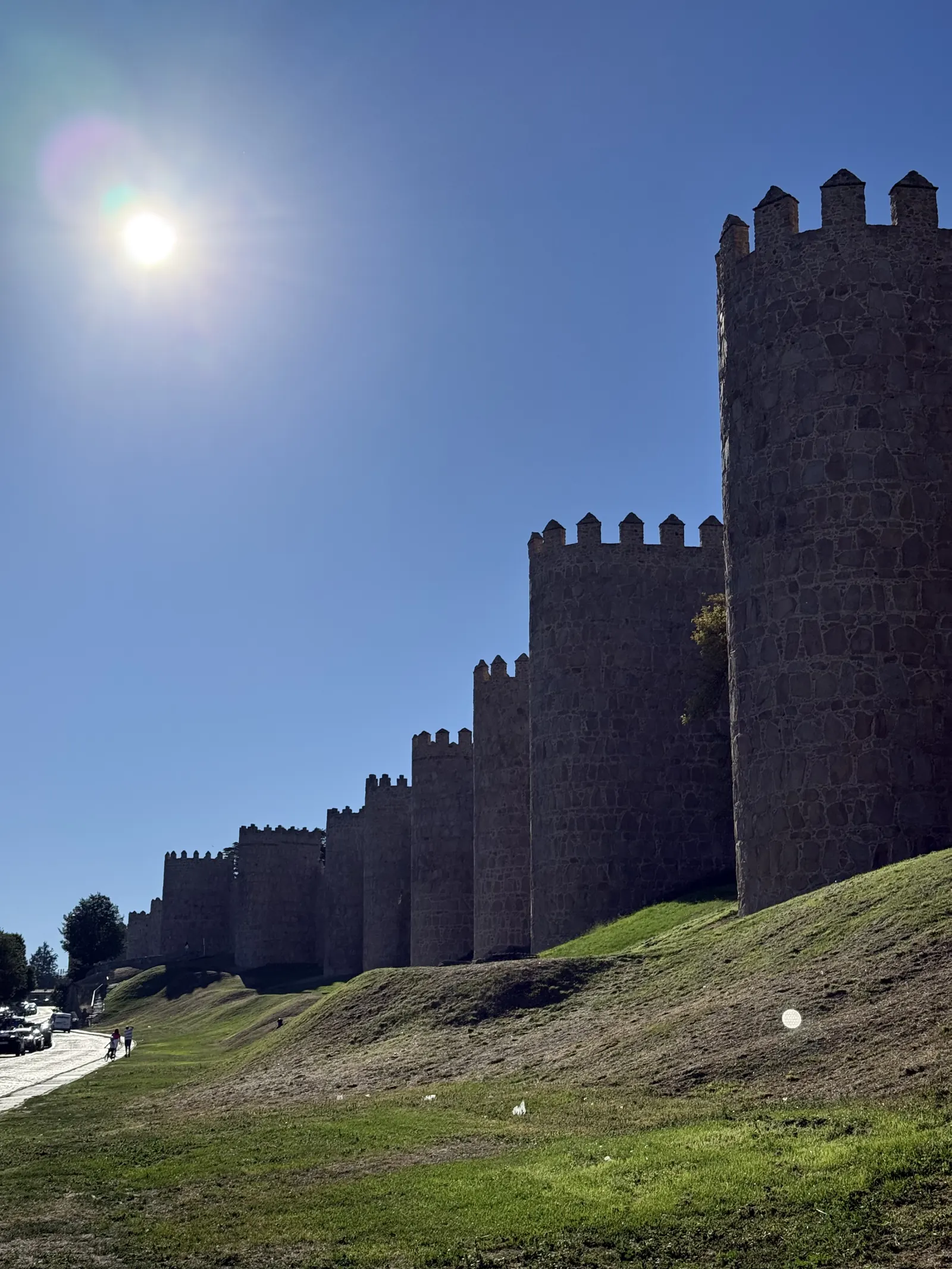 Cubos almenados del lienzo norte de la muralla de Ávila a contraluz con el sol de la mañana sobre el talud. Foto propia La Maleta Inquieta, septiembre 2026.