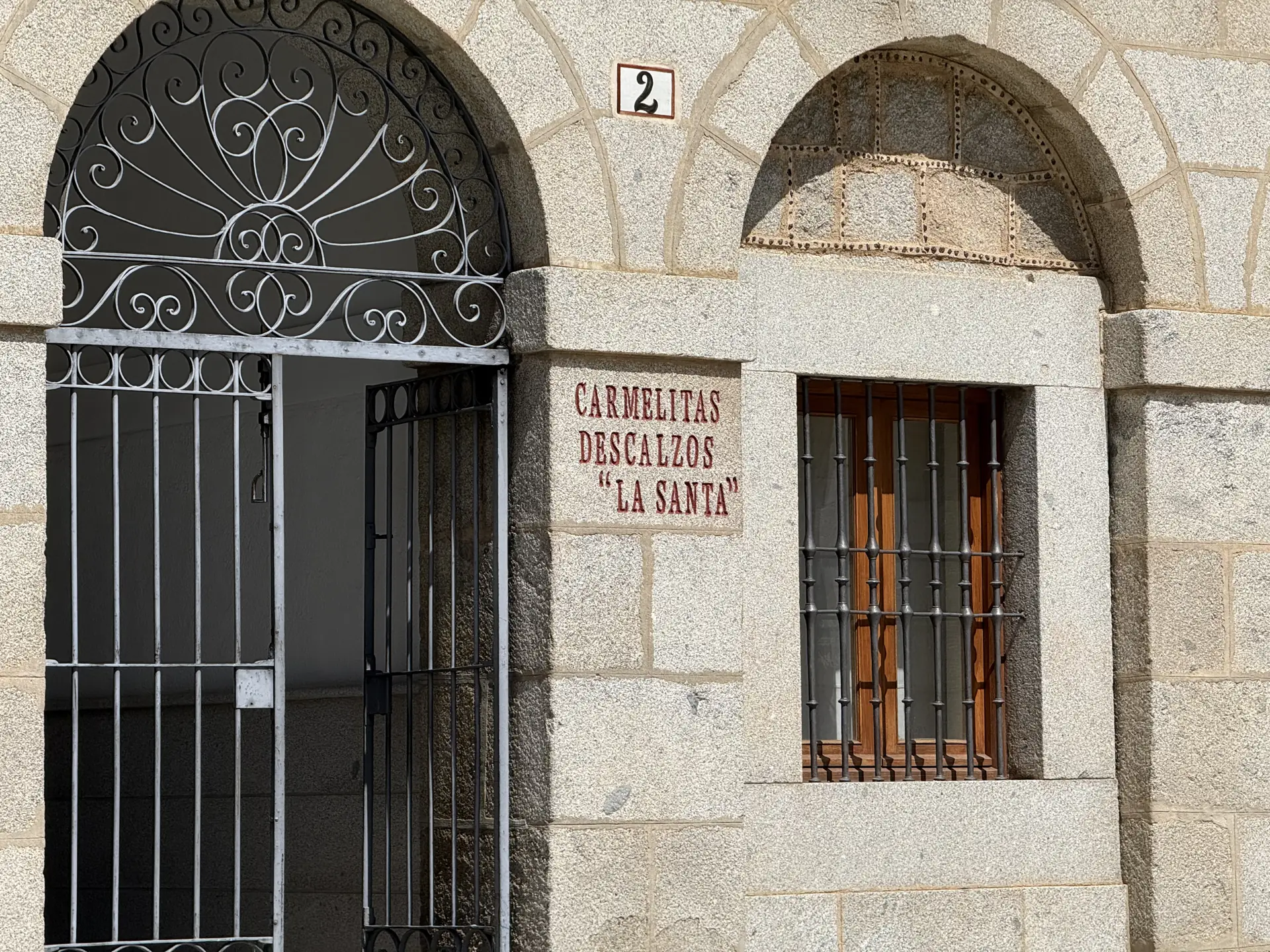 Cancela de forja bajo un arco y rótulo Carmelitas Descalzos La Santa en el soportal del convento de Ávila. Foto propia La Maleta Inquieta, septiembre 2026.