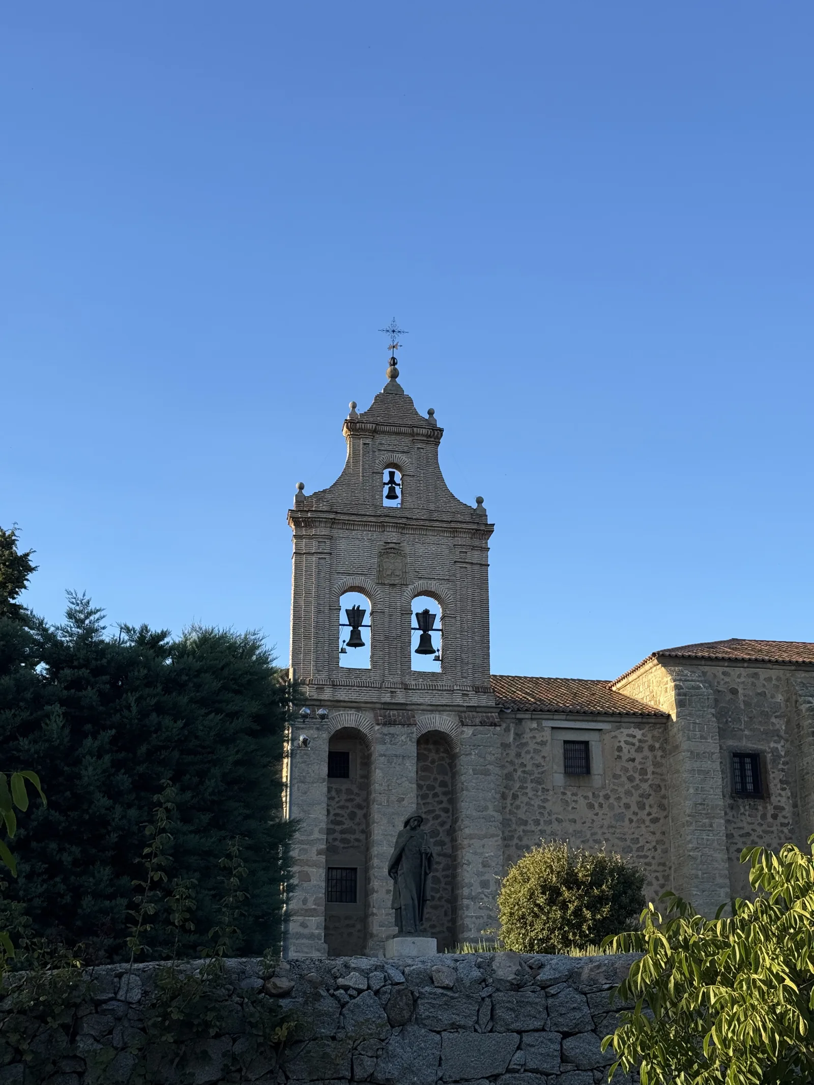 Espadaña con campanas del monasterio de la Encarnación de Ávila y estatua de Santa Teresa, con luz de tarde. Foto propia La Maleta Inquieta, septiembre 2026.