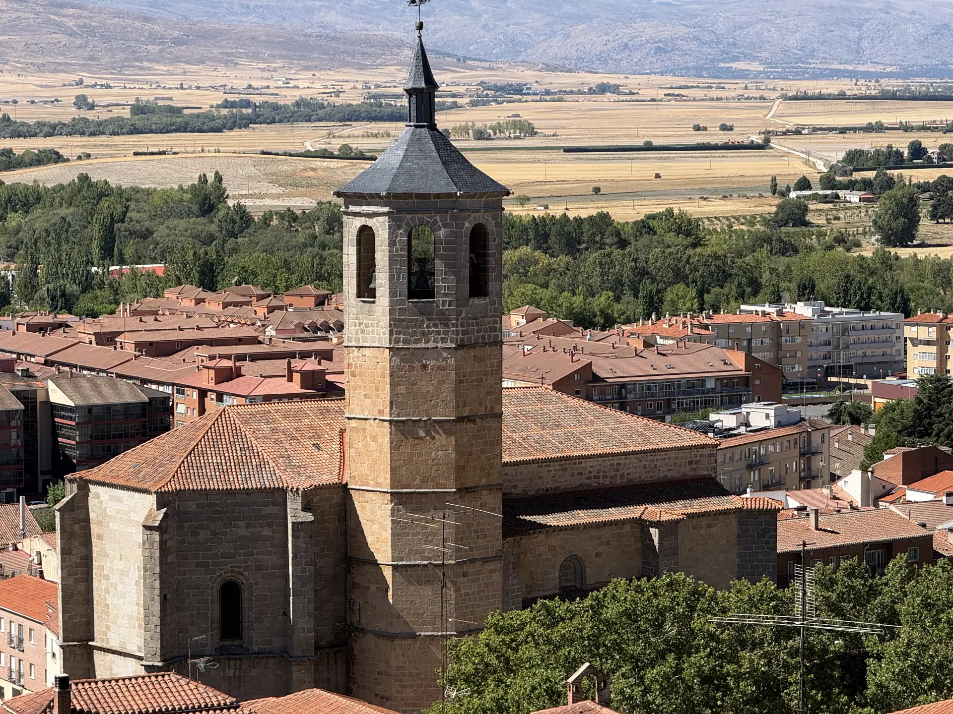 Torre octogonal con chapitel de pizarra de la iglesia de Santiago de Ávila, con el valle Amblés y la sierra detrás. Foto propia La Maleta Inquieta, septiembre 2026.