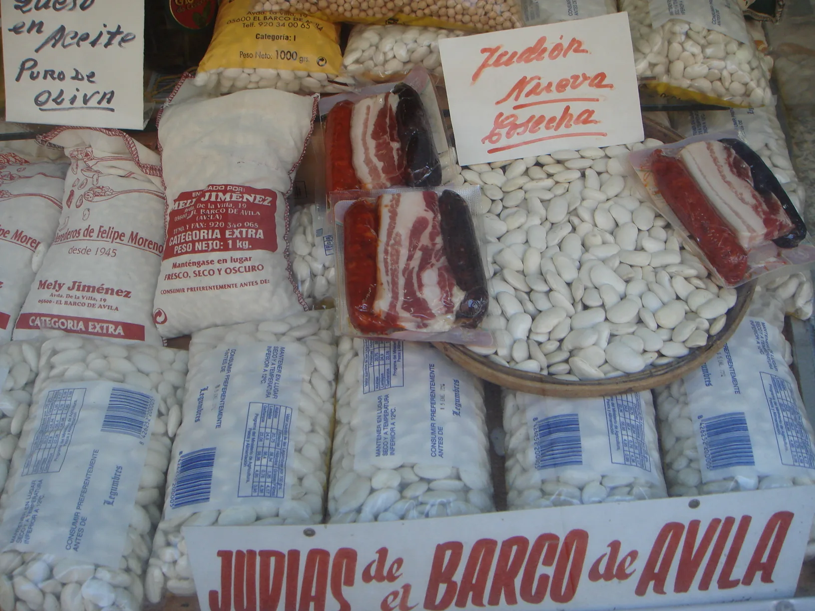 Sacos de judías de El Barco de Ávila con su etiqueta de denominación y carteles de judión en un puesto de venta