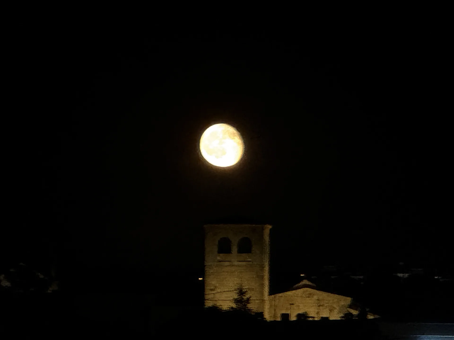 Luna casi llena sobre la torre iluminada de la iglesia románica de San Andrés de Ávila, en plena noche. Foto propia La Maleta Inquieta, septiembre 2026.
