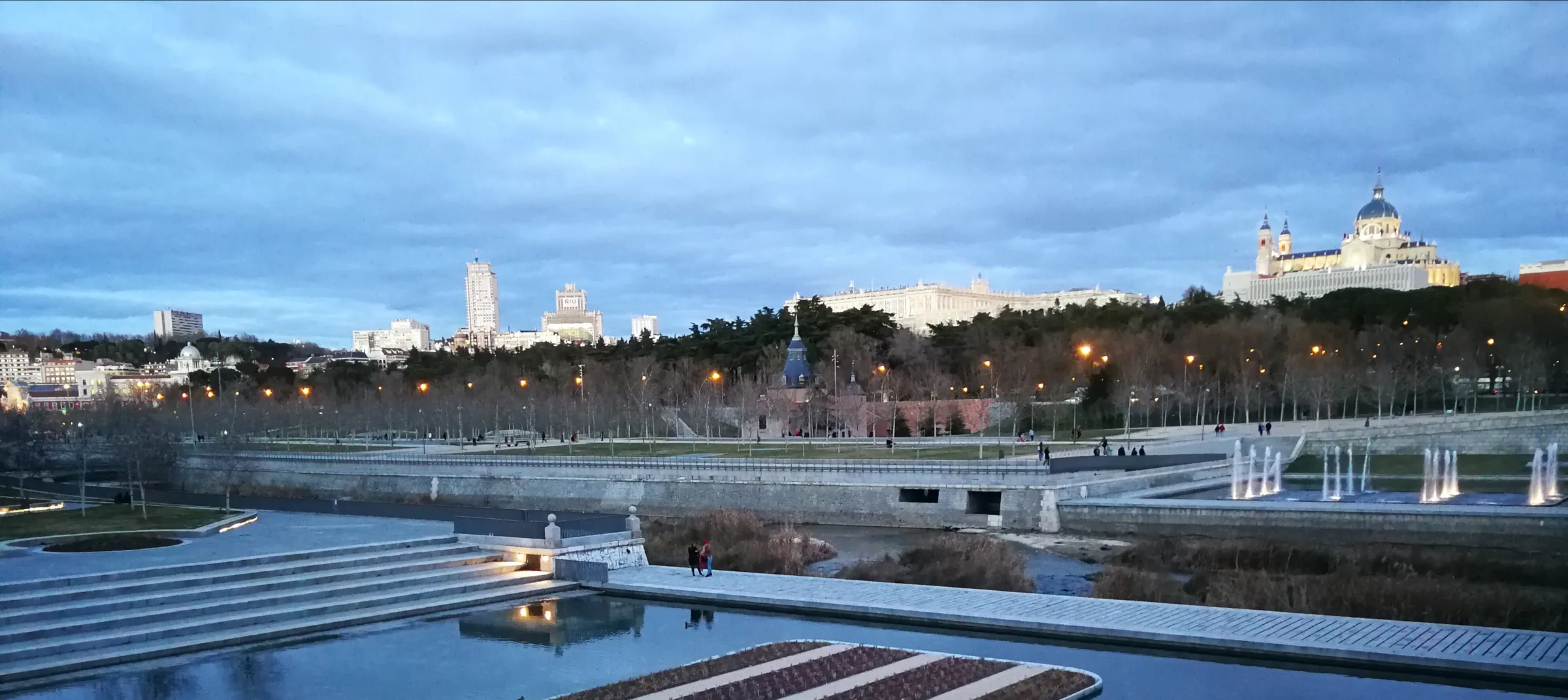 Madrid Río al anochecer con el Palacio Real y la catedral de la Almudena iluminados sobre el parque del Manzanares
