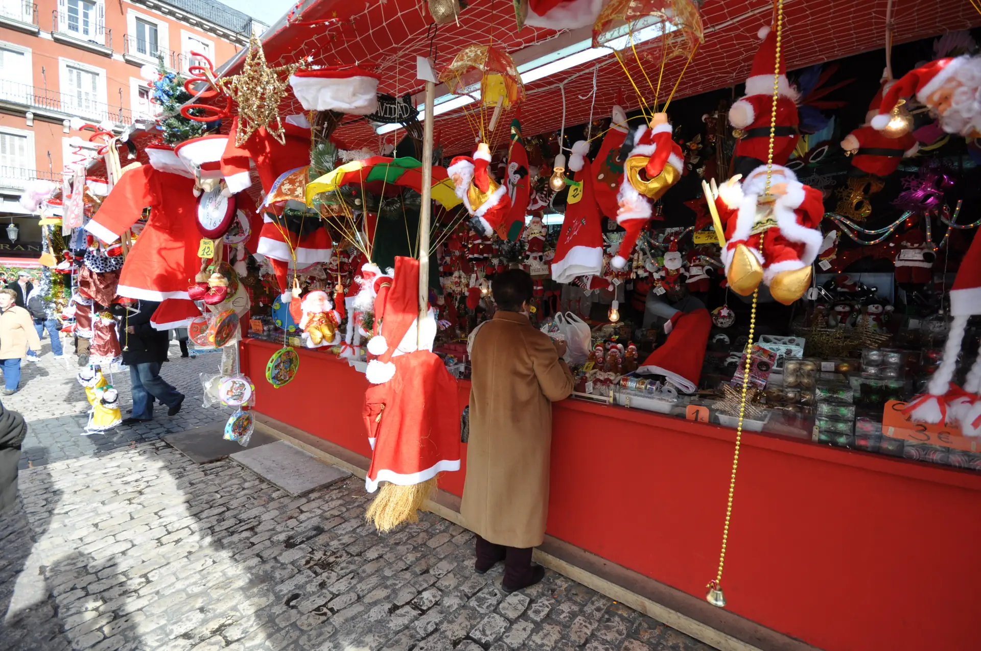 Puesto rojo del mercado de Navidad de la Plaza Mayor de Madrid con adornos de Papá Noel colgados