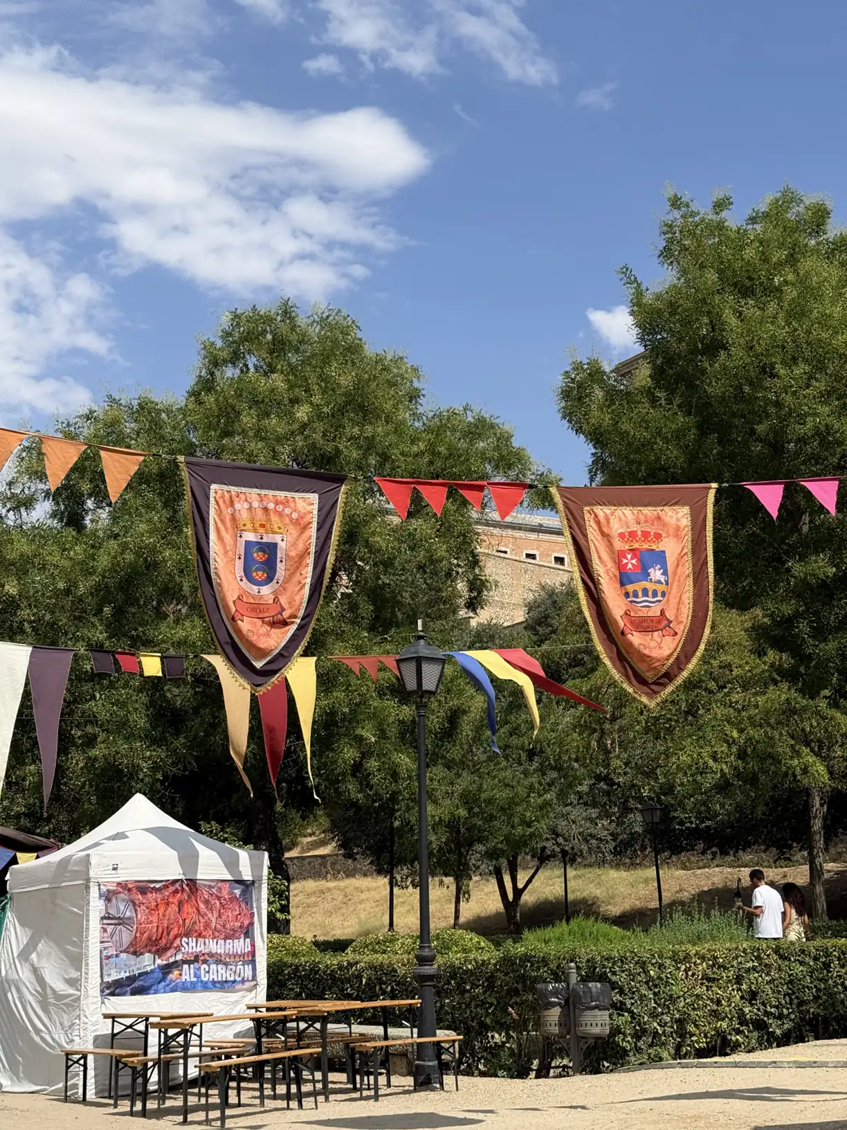 Escudos heráldicos y banderines del Mercado Medieval de Toledo con la muralla al fondo. Foto propia La Maleta Inquieta, septiembre 2026.