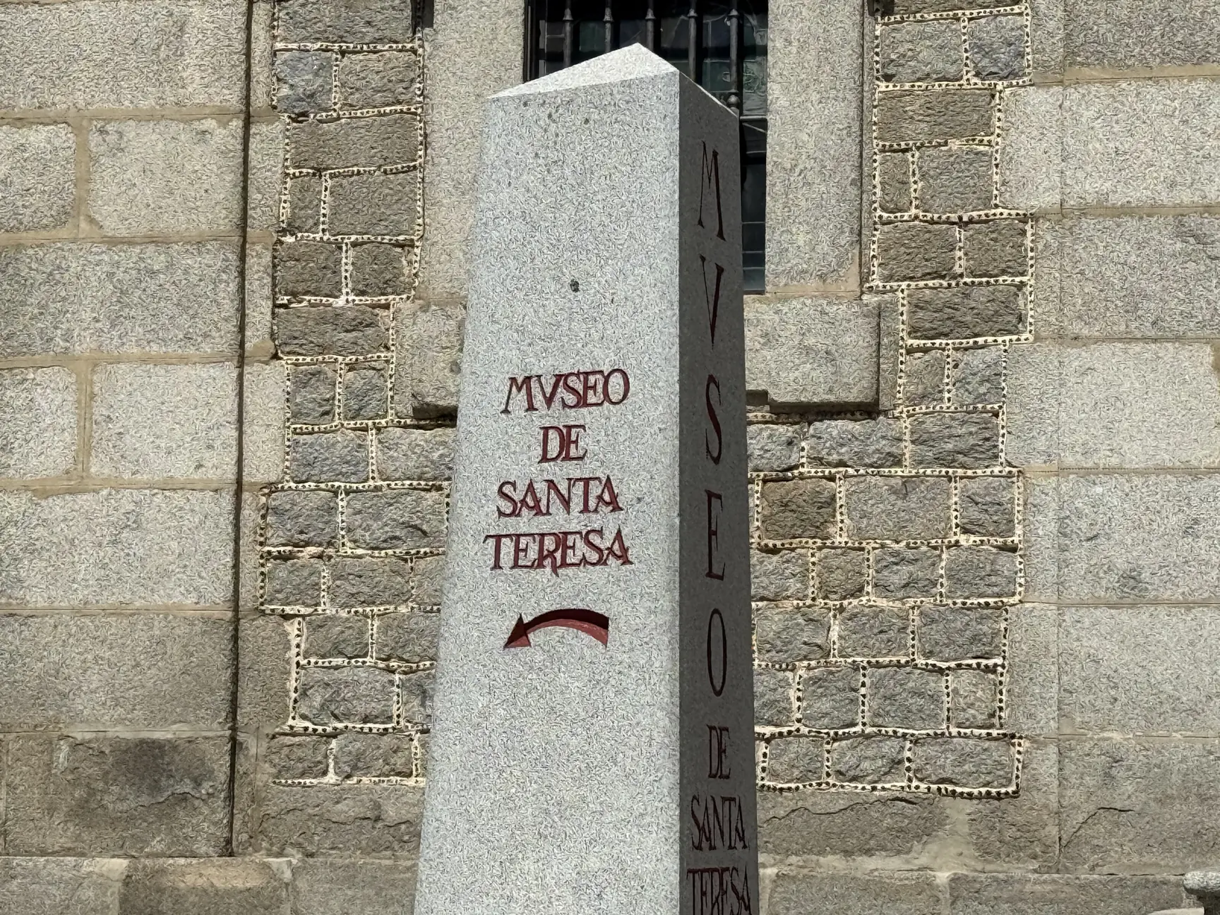 Hito de granito con el rótulo Museo de Santa Teresa en rojo y una flecha, junto al muro del convento en Ávila. Foto propia La Maleta Inquieta, septiembre 2026.